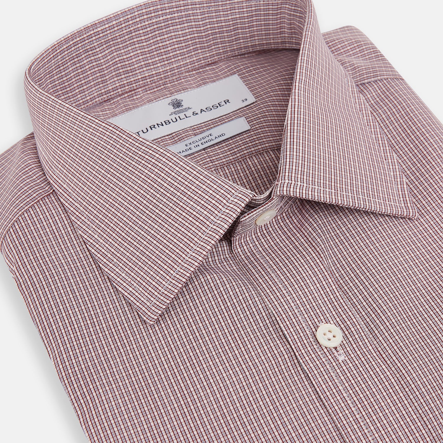 Image 2 of product The Turnbull & Asser Burgundy Micro Shadow Check Mayfair Shirt features long sleeves, a classic collar, and white buttons. In light red and white shades, this button-up is perfect for formal wear and is shown laid flat against a white background.