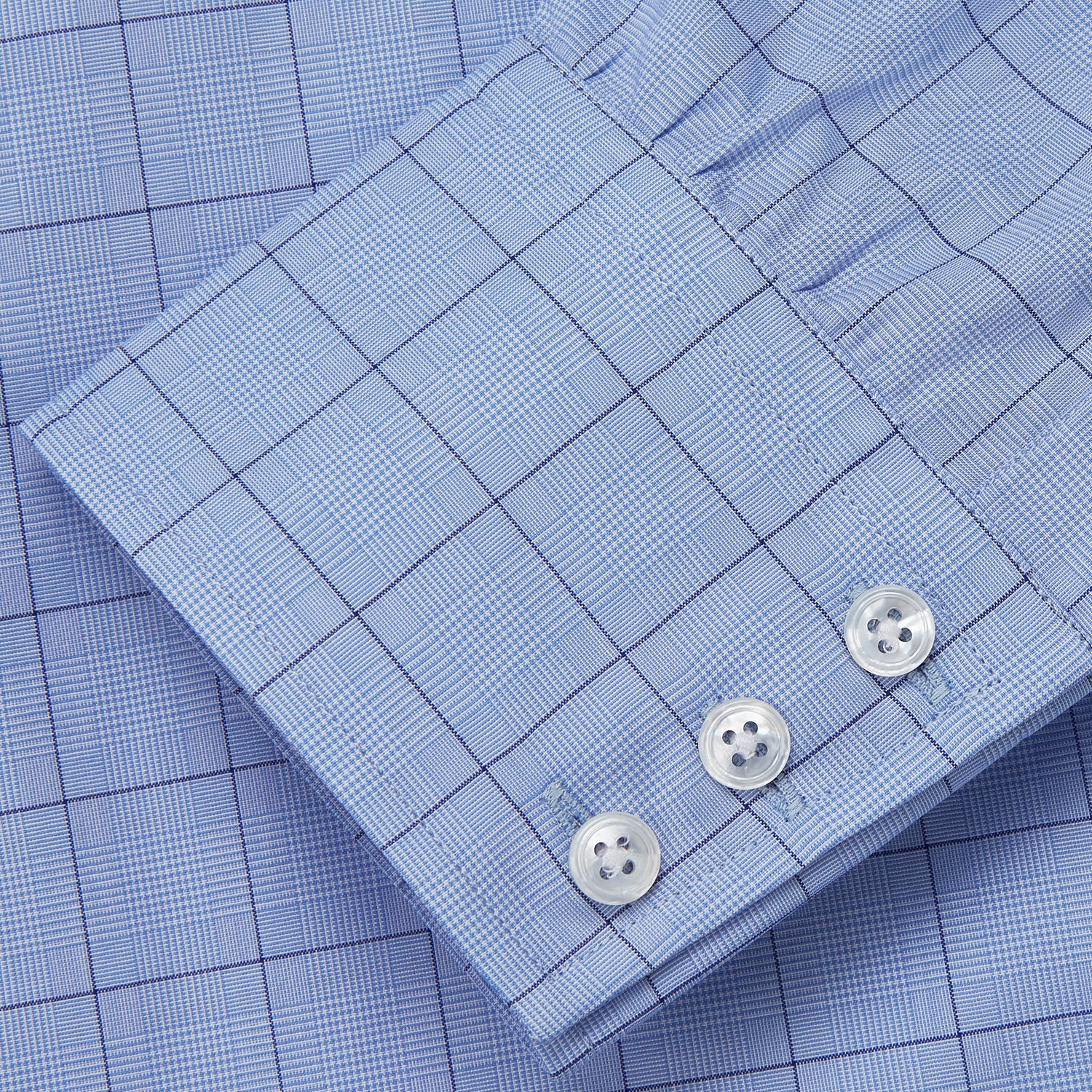 Image 4 of product The Blue Prince of Wales Check Mayfair Shirt by Turnbull & Asser is a light blue formal long-sleeve shirt with a subtle check pattern, button-down front, and buttoned cuffs, shown laid flat on a white background.
