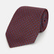 The Red Multi-Floral Silk Tie by Turnbull & Asser features a blue and white geometric pattern and is shown rolled up against a plain white background.