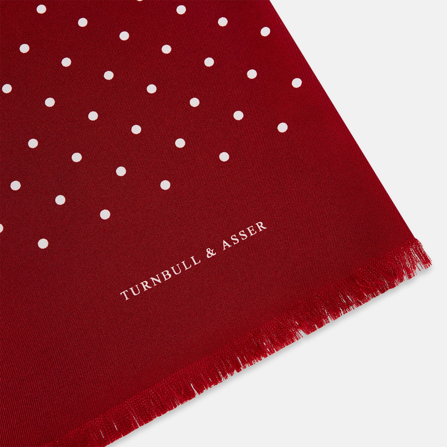 Image 2 of product The Burgundy and White Spotted Silk Scarf by Turnbull & Asser features a gradient of white polka dots, short fringed edges, and the brand's name near the ends—a timeless classic foulard.