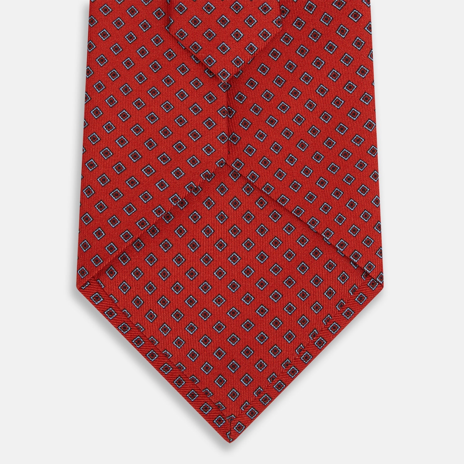 Image 3 of product The Turnbull & Asser Red and Blue Square-Patterned Silk Tie is rolled up on a plain white background.