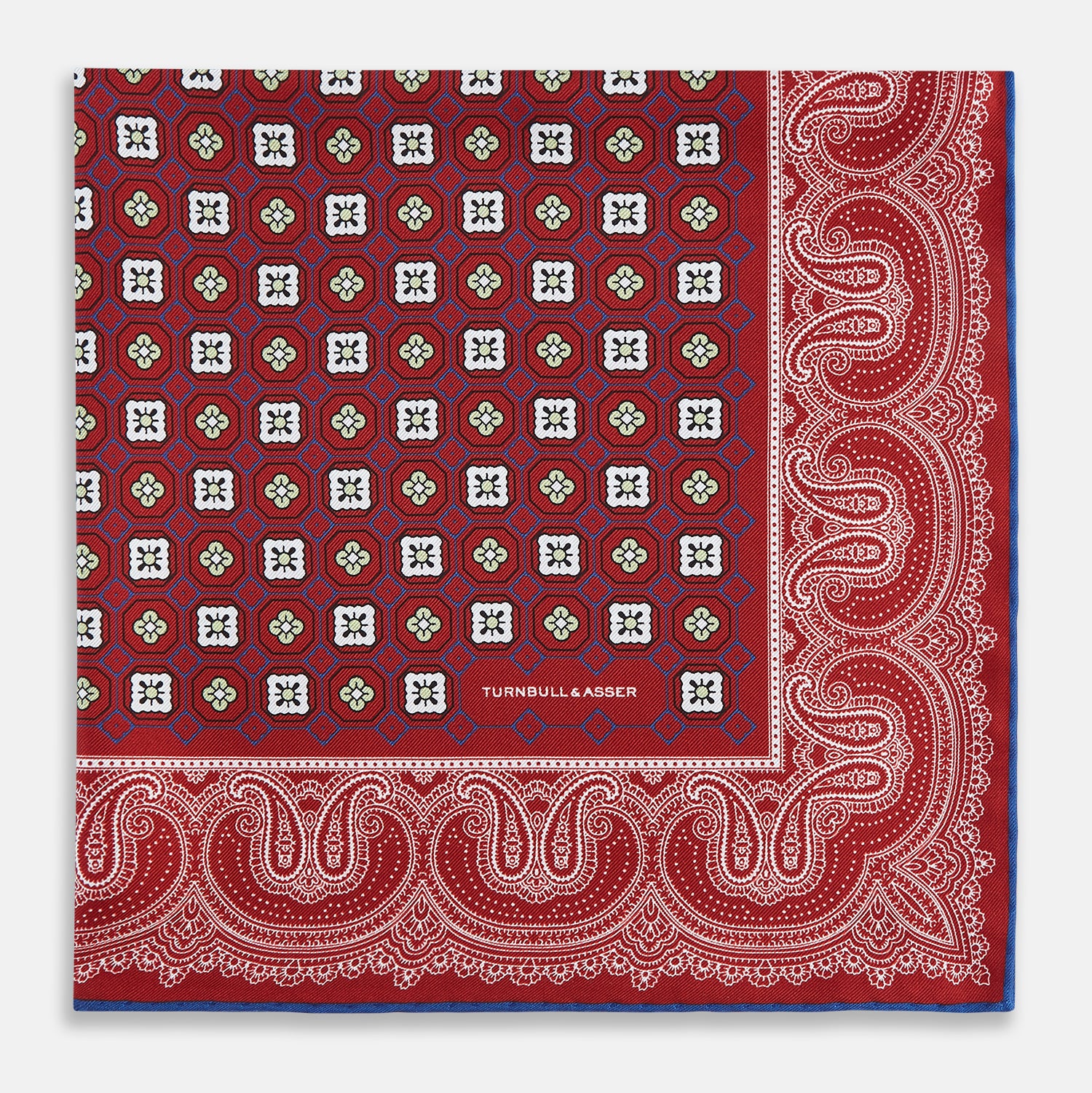 Image 3 of product The Turnbull & Asser Red Floral Tile and Paisley Silk Pocket Square features red silk with white and green paisley and geometric patterns, a blue border, a folded corner revealing both sides, branding in white, and is handcrafted in England.