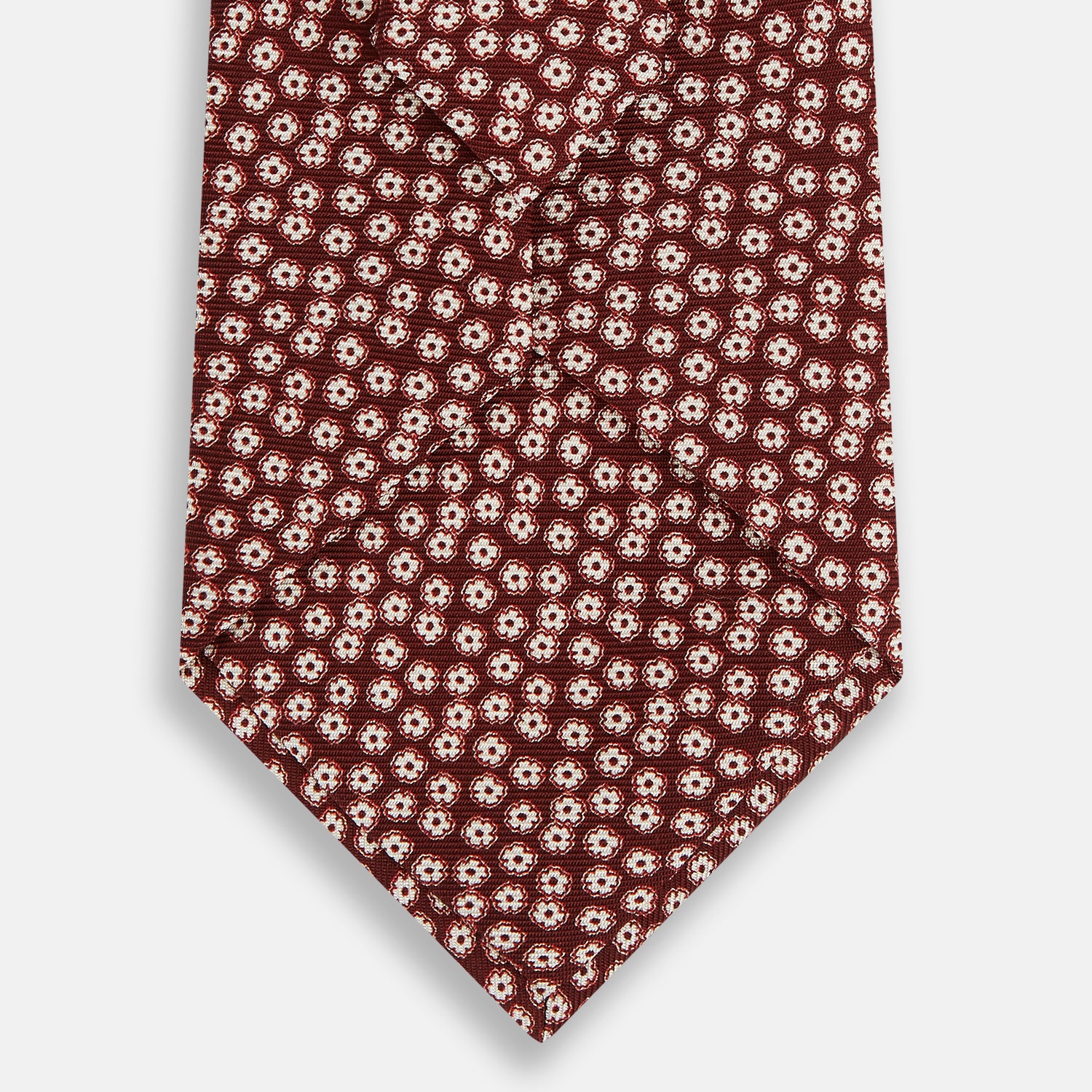 Image 3 of product Turnbull & Asser's Burgundy Flower Patterned Silk Tie features small white and light red floral circles, shown rolled on a plain white background.