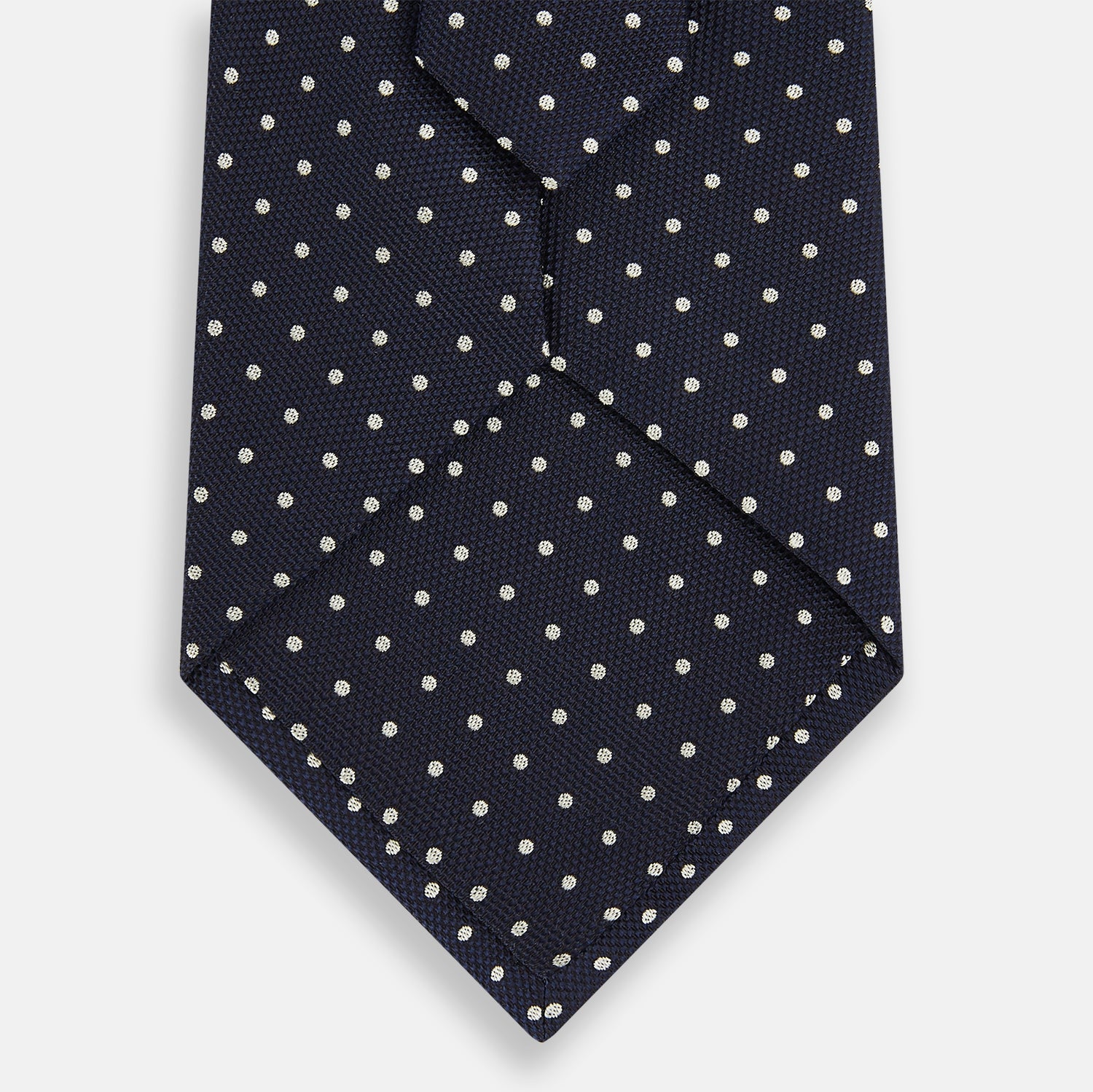 Image 3 of product The Silver and Navy Micro Dot Silk Tie by Turnbull & Asser features a refined micro dot pattern, perfect for adding a classic accent to formal attire. Shown neatly rolled on a white background.