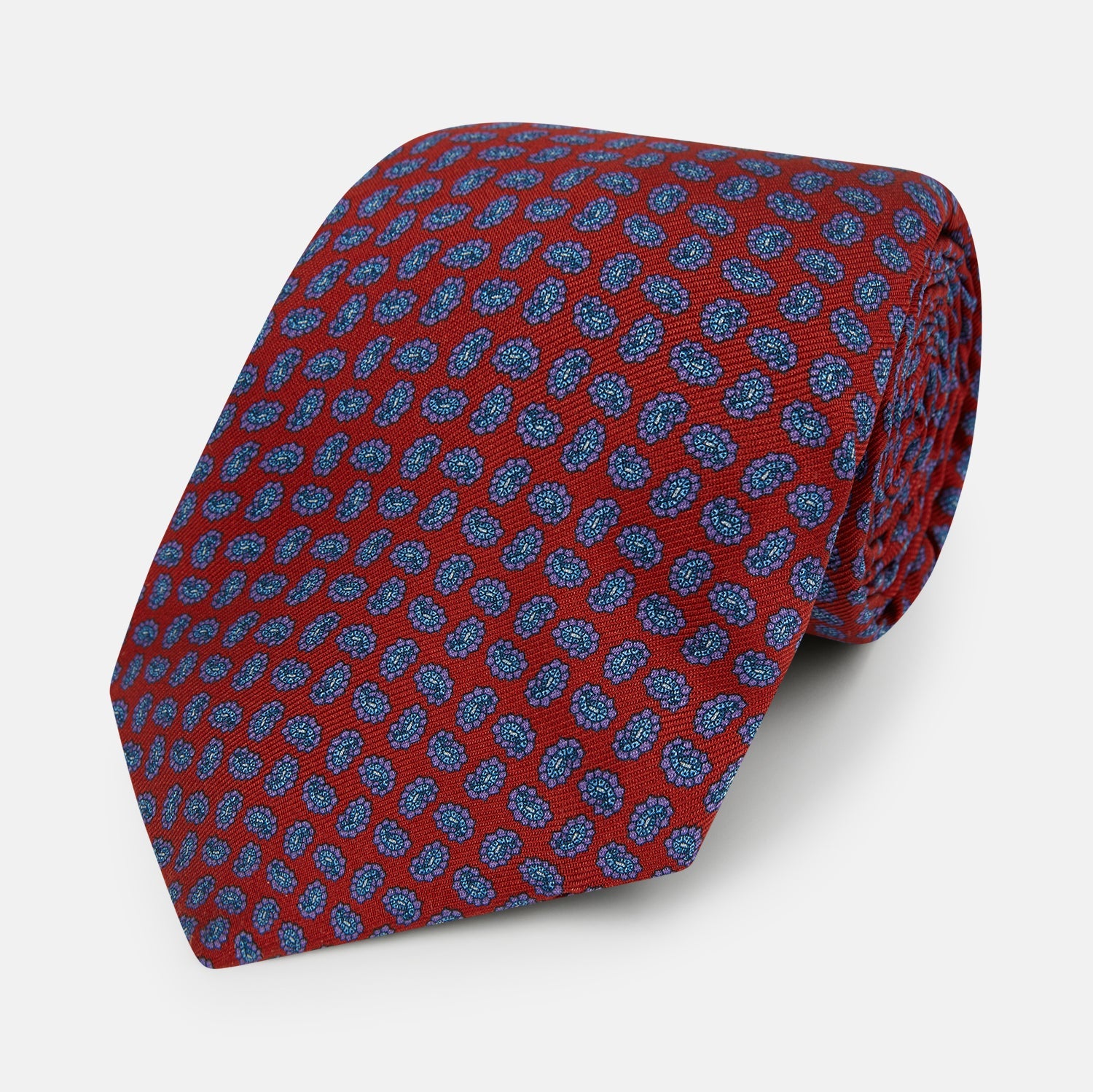 Image 1 of product The Turnbull & Asser Red and Purple Miniature Paisley Silk Tie is neatly rolled with the pointed end facing forward.