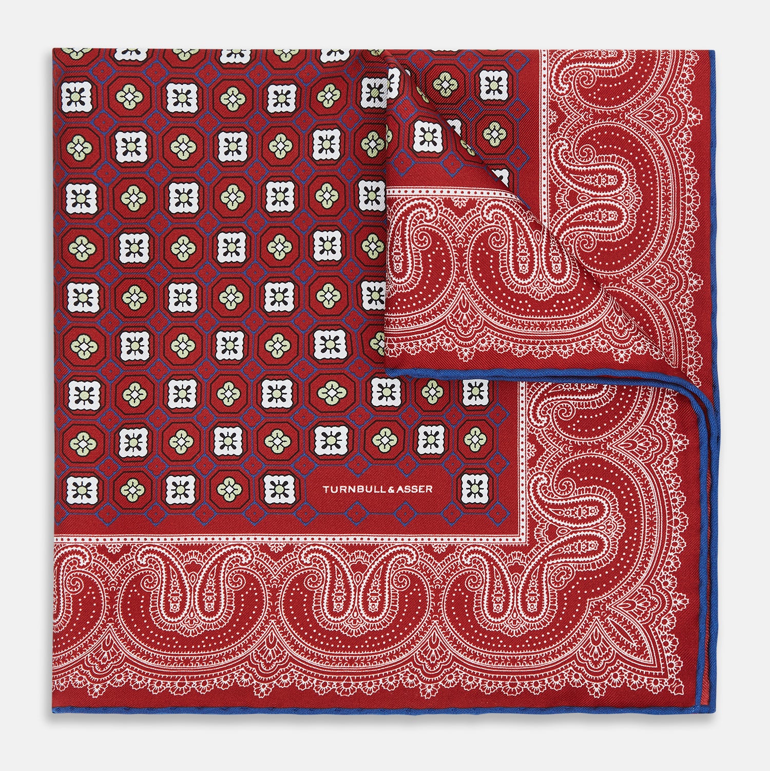 Image 5 of product The Turnbull & Asser Red Floral Tile and Paisley Silk Pocket Square features red silk with white and green paisley and geometric patterns, a blue border, a folded corner revealing both sides, branding in white, and is handcrafted in England.