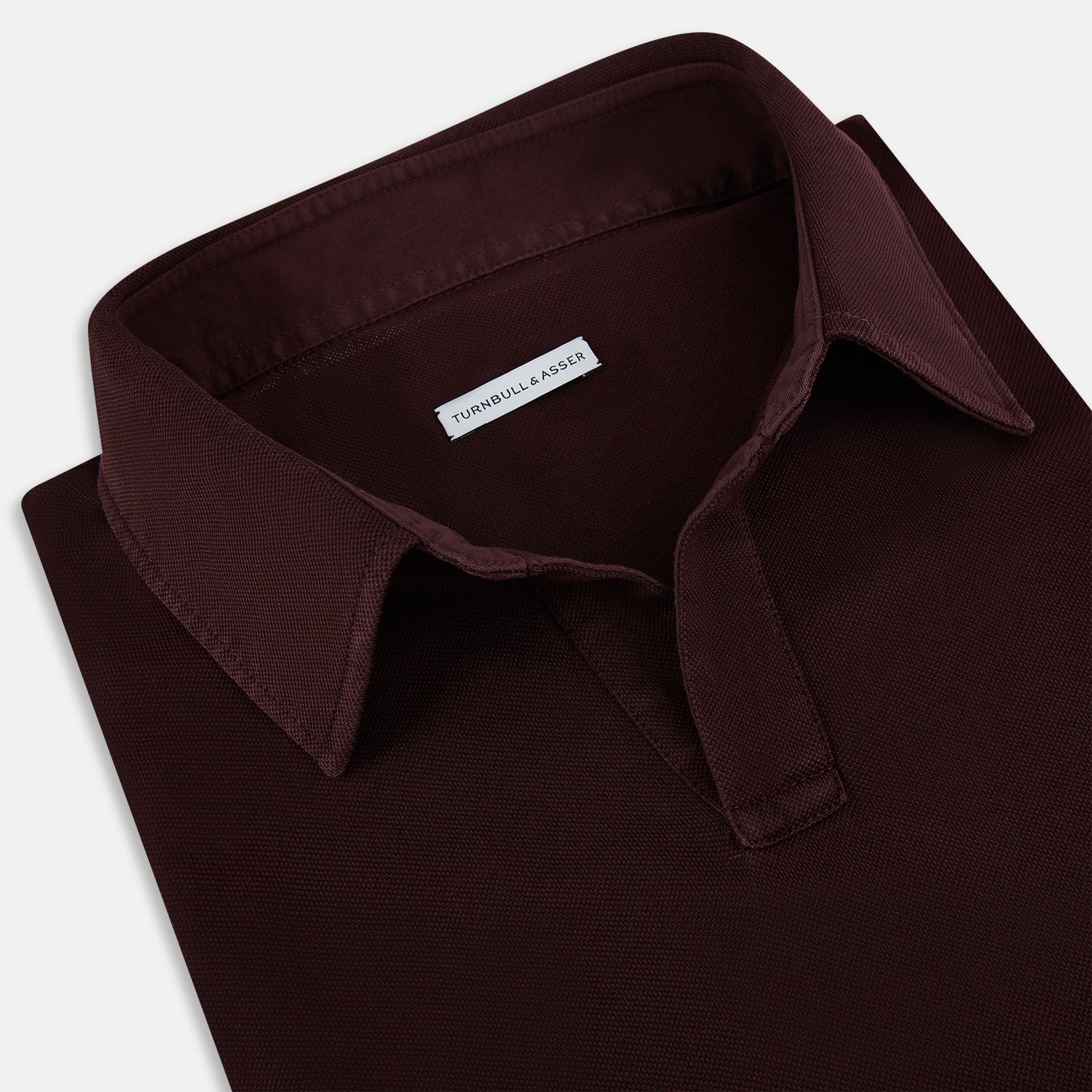 Image 2 of product The Turnbull & Asser Burgundy Rugby Polo Shirt is a long-sleeve, pure cotton collared top with no visible buttons, shown laid flat on a white background.
