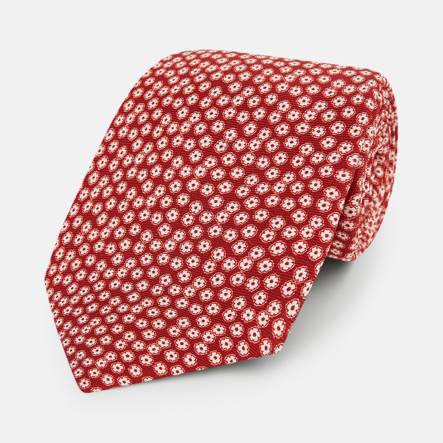 Image 1 of product The Red Flower Patterned Silk Tie by Turnbull & Asser, crafted from fine English silk, features a delicate white floral design and is neatly rolled on a white background.