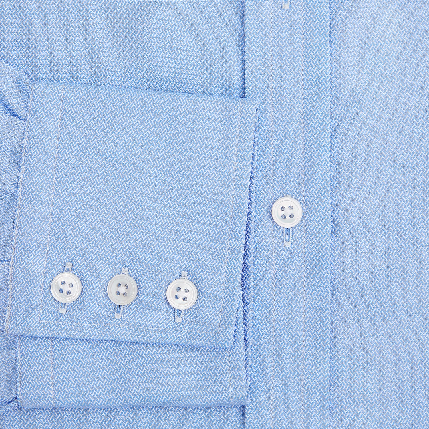 Image 4 of product The Blue Herringbone Mayfair Shirt by Turnbull & Asser features light blue and white stripes, long sleeves, a classic collar, white buttons, and buttoned cuffs. Shown on a plain white background, it's perfect for formal occasions.