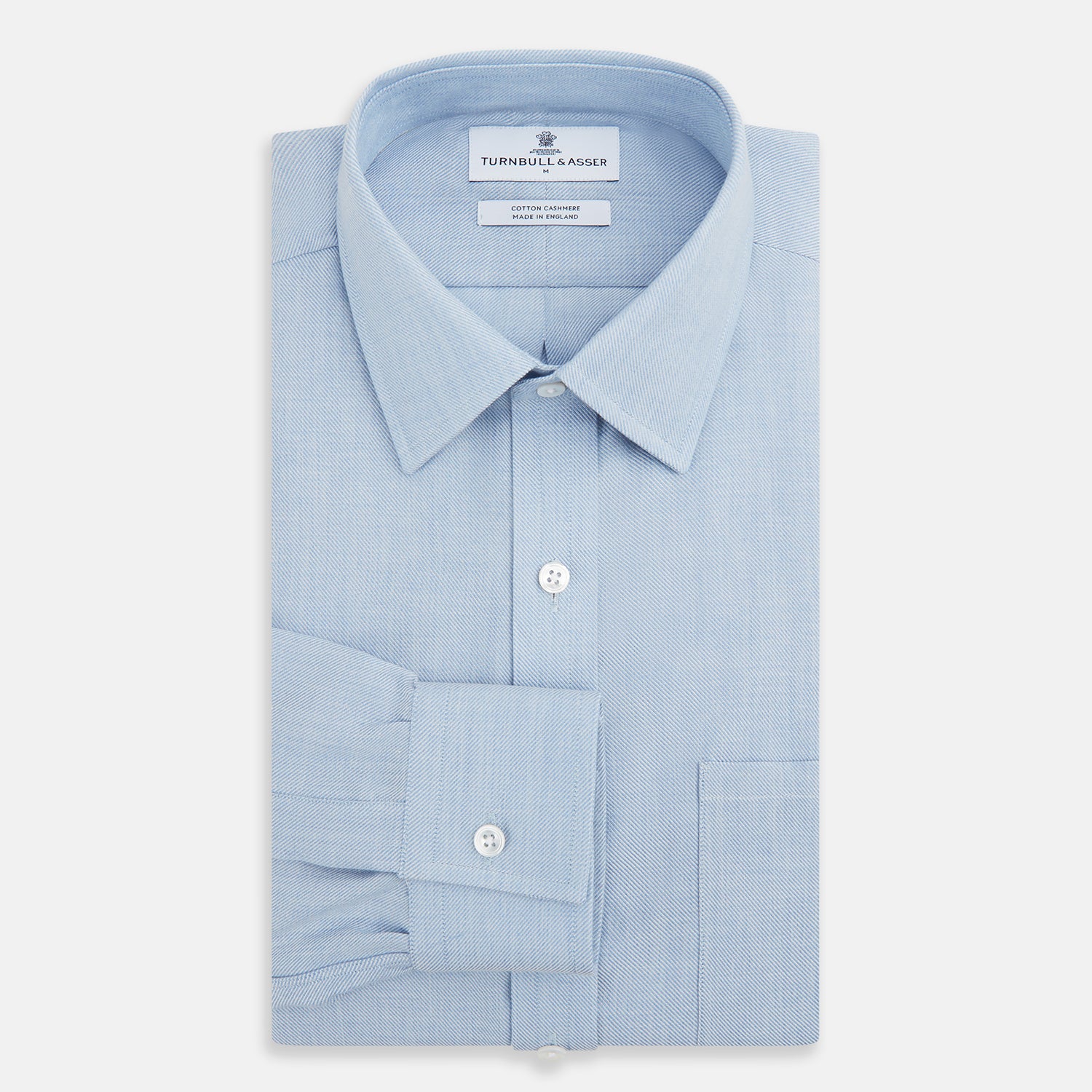Image 4 of product The Turnbull & Asser Pale Blue Cotton Cashmere Derby Collar Richmond Shirt features a soft cotton-cashmere blend, derby collar, white buttons, left chest pocket, and buttoned cuffs, shown laid flat on a white background.