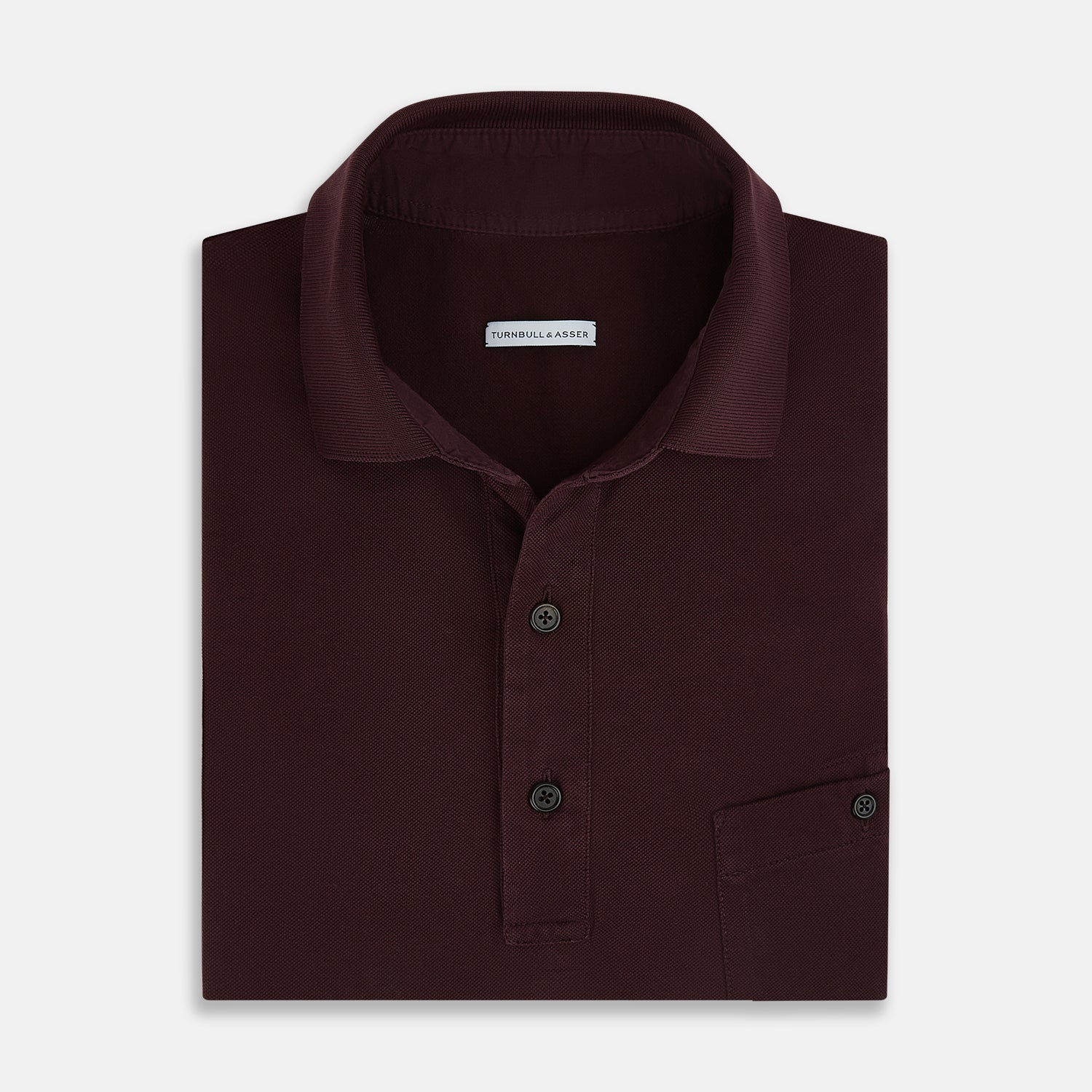 Image 4 of product The Turnbull & Asser Burgundy Polo Shirt is crafted from soft cotton jersey with short sleeves, a classic collar, three front buttons, and a small buttoned chest pocket, shown flat on a white background.