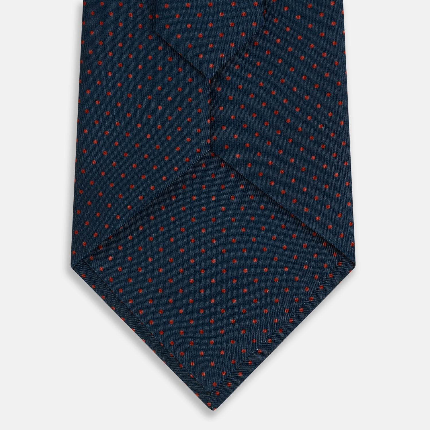 Image 3 of product The Turnbull & Asser Navy and Red Polka Dot Silk Tie, rolled neatly on a light background, highlights classic British craftsmanship with its refined pattern.