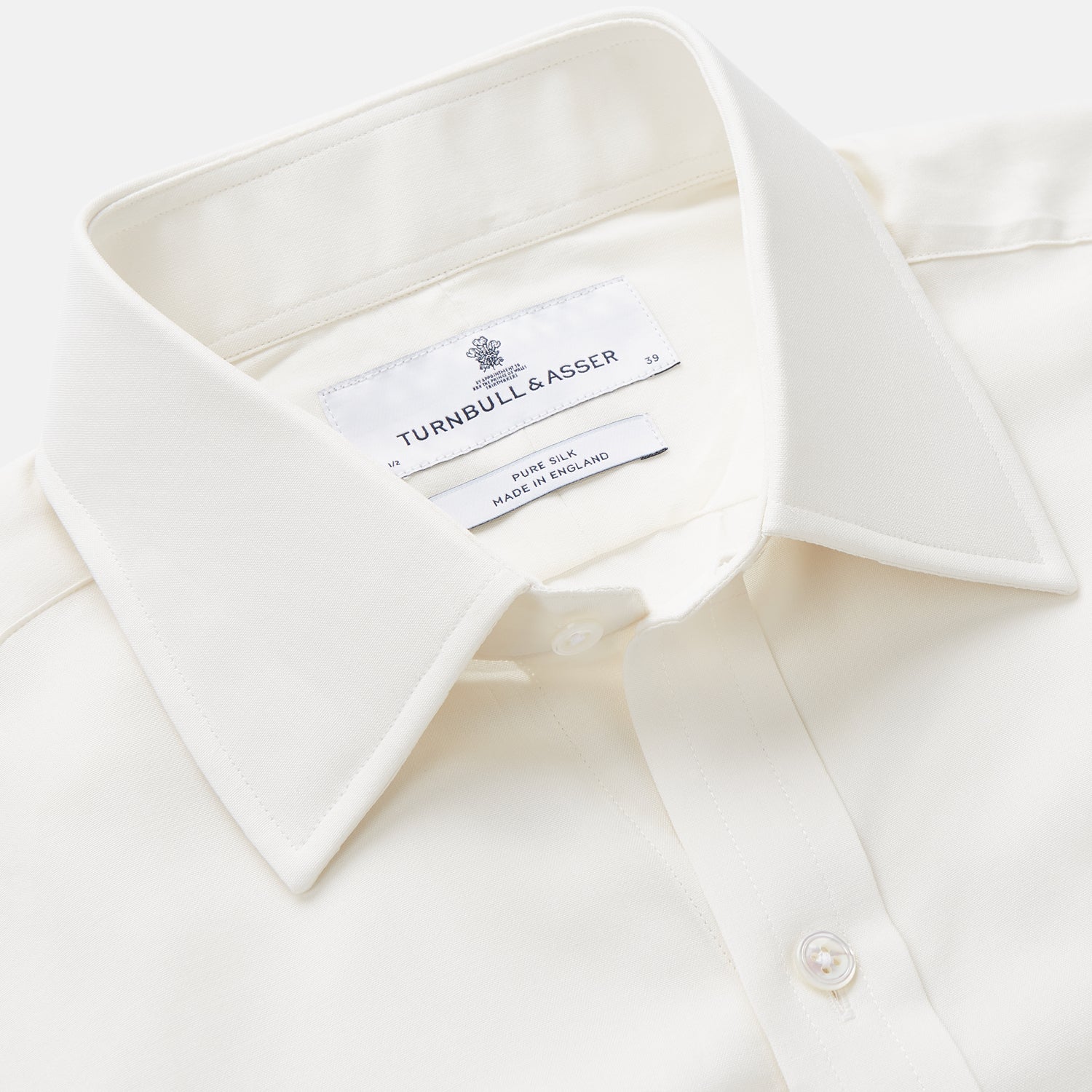 Image 2 of product The Cream Silk Whitby Shirt by Turnbull & Asser features a pointed collar, buttoned front and cuffs, and long sleeves, shown in Whitby Fit and laid flat on a white background.