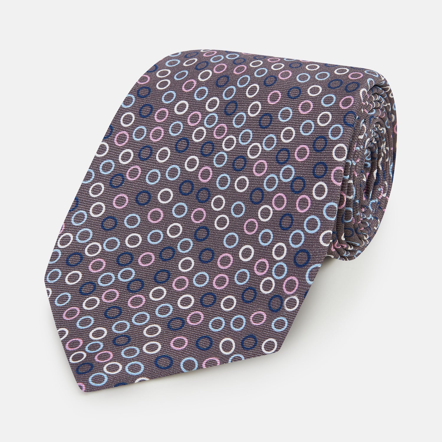 Image 1 of product The Turnbull & Asser Purple and Blue Circle Ash Silk Tie features small blue, pink, and white circles on a dark purple background, adding an elegant touch when displayed on a light surface.