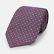 The Turnbull & Asser Lilac and Purple Micro Dot Silk Tie, featuring small white dots, is a stylish accessory for smart attire. Displayed rolled-up on a light background.