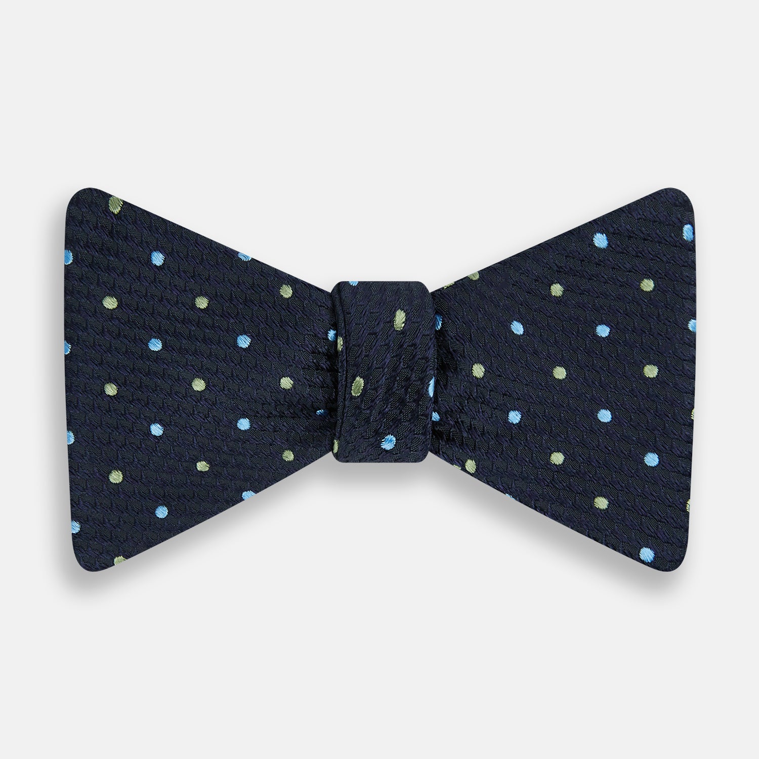 Image 1 of product The Turnbull & Asser Lime Green and Sky Blue Spot Silk Bow Tie features a textured navy background with light blue and lime green polka dots, shown on a white background—a timeless men's accessory.