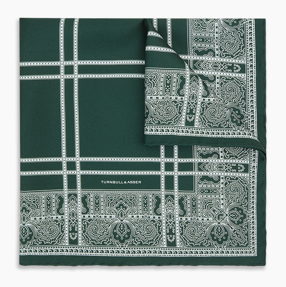 Image 5 of product Turnbull & Asser’s Forest Green Paisley Bandana Patterned Silk Pocket Square is handcrafted in England, featuring an intricate white geometric and paisley design with the brand name printed in one corner.