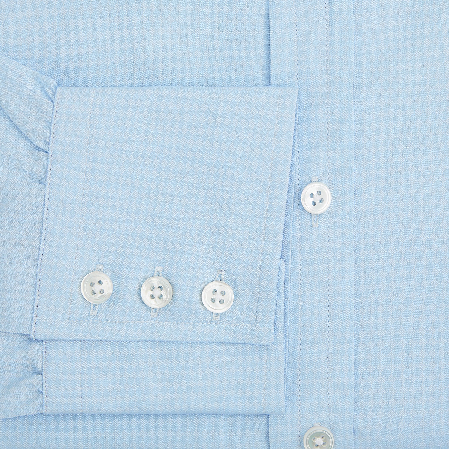 Image 4 of product The Pale Blue Rhombus Mayfair Shirt by Turnbull & Asser features long sleeves, a classic collar, white buttons, and buttoned cuffs, shown laid flat on a white background.