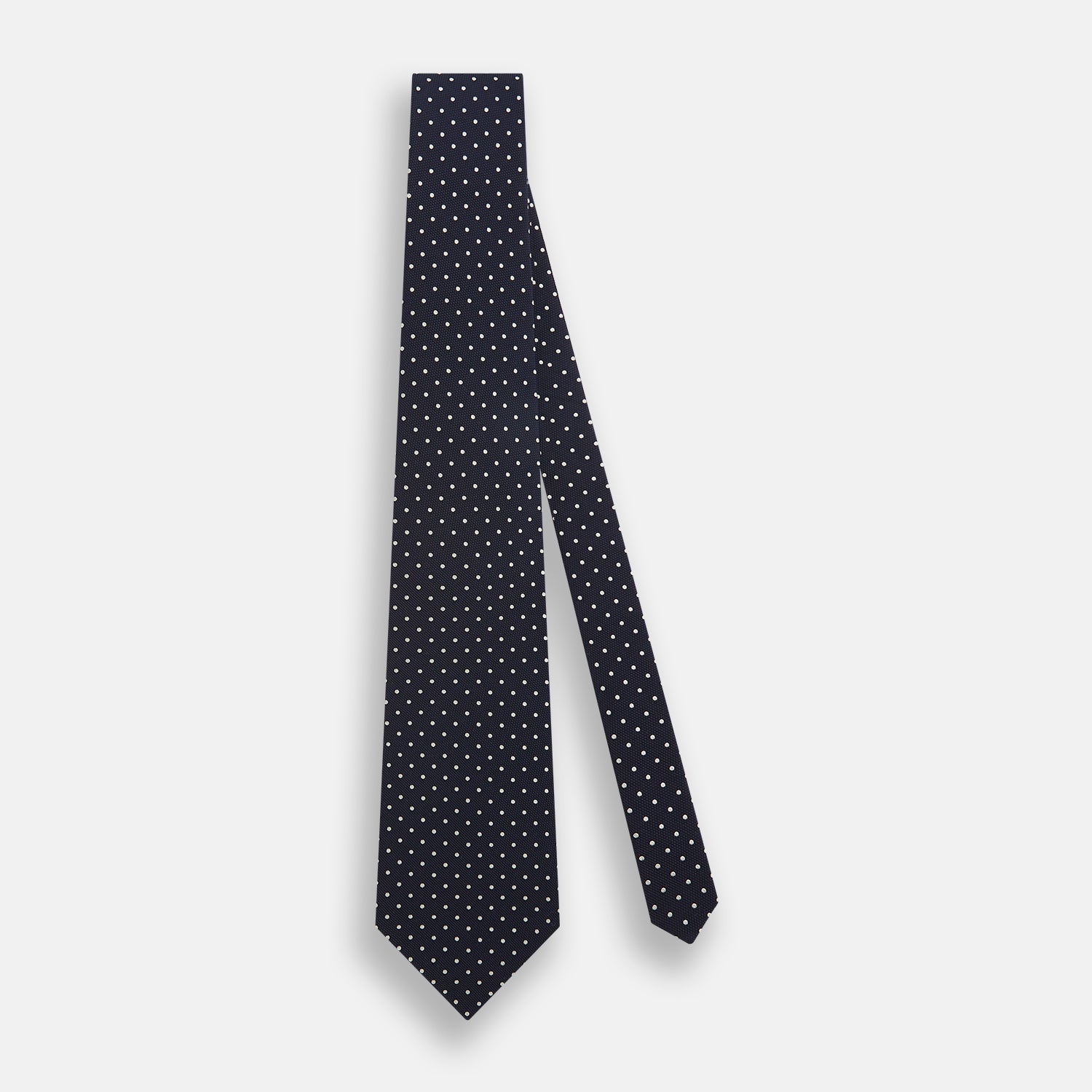 Image 2 of product The Silver and Navy Micro Dot Silk Tie by Turnbull & Asser features a refined micro dot pattern, perfect for adding a classic accent to formal attire. Shown neatly rolled on a white background.