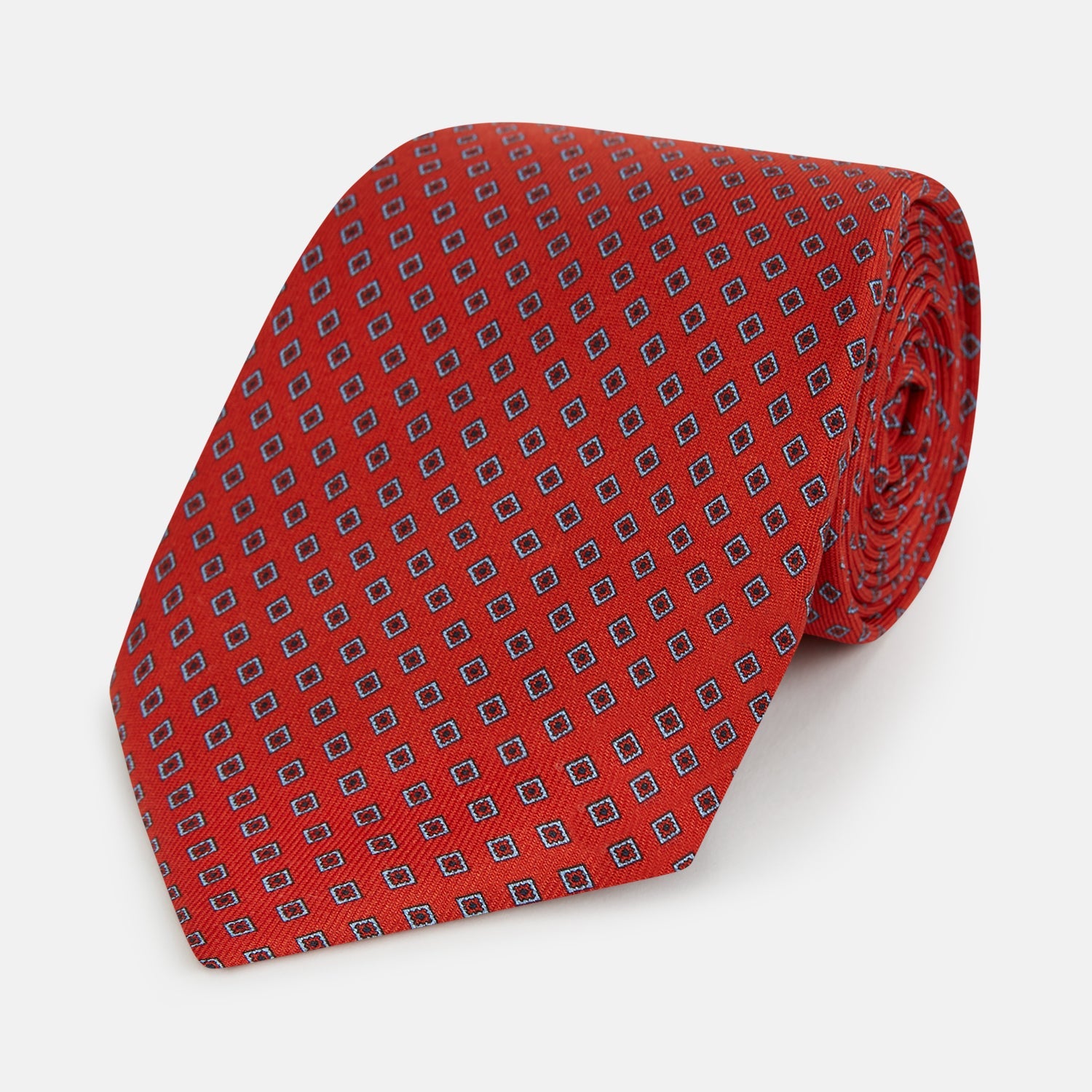 Image 1 of product The Turnbull & Asser Red and Blue Square-Patterned Silk Tie is rolled up on a plain white background.