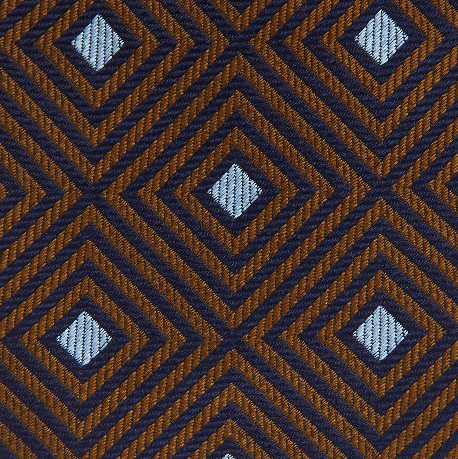 Image 4 of product The Tomorrow Never Dies Square Silk Tie by Turnbull & Asser, as seen on James Bond, features a brown and blue geometric diamond pattern on a dark background—an ideal accessory for any Bond-inspired look. Displayed rolled on a plain white surface.