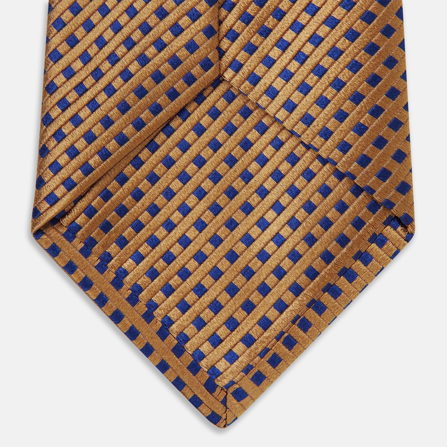 Image 5 of product The Turnbull & Asser Tomorrow Never Dies Diamond Silk Tie, as seen on James Bond, features a gold and navy checkered pattern—an ideal gift for any Bond fan. Displayed rolled against a plain white background.
