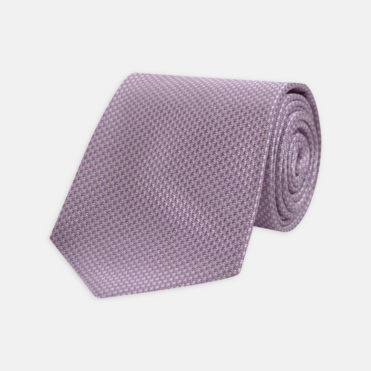 Image 1 of product The Turnbull & Asser Lilac Houndstooth Silk Tie features a subtle houndstooth pattern and elegant silk weave—ideal for elevating your favorite office shirt. Displayed rolled on a white background.