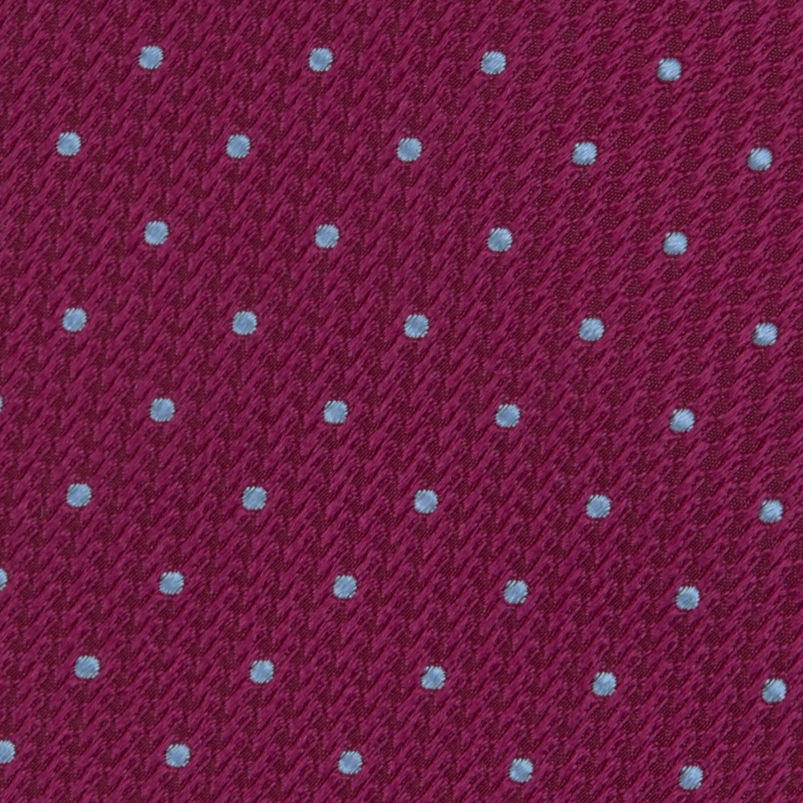 Image 3 of product The Turnbull & Asser Dark Pink and Blue Spot Lace Silk Tie features small, evenly spaced blue dots on dark pink silk, shown rolled up against a white background.