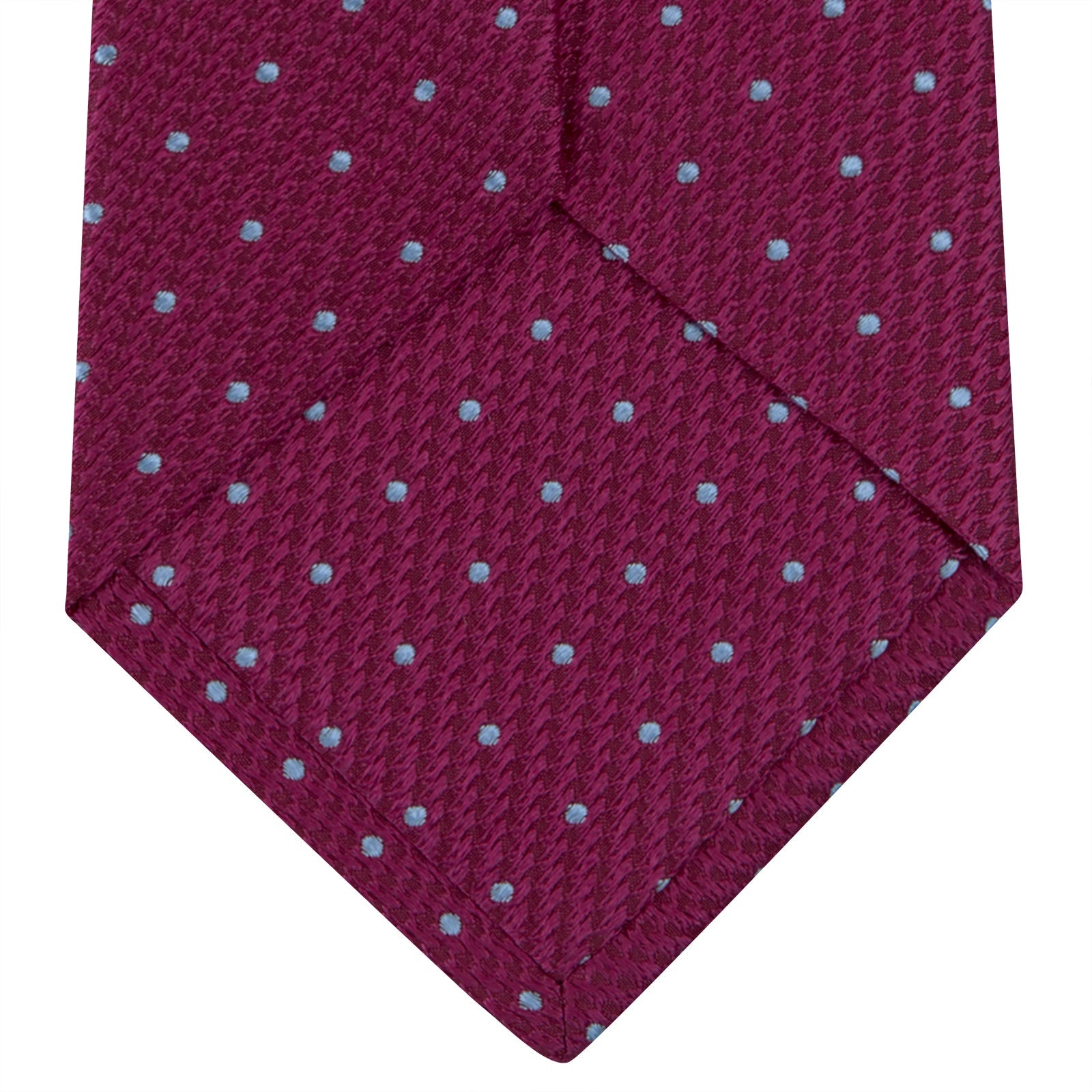 Image 4 of product The Turnbull & Asser Dark Pink and Blue Spot Lace Silk Tie features small, evenly spaced blue dots on dark pink silk, shown rolled up against a white background.