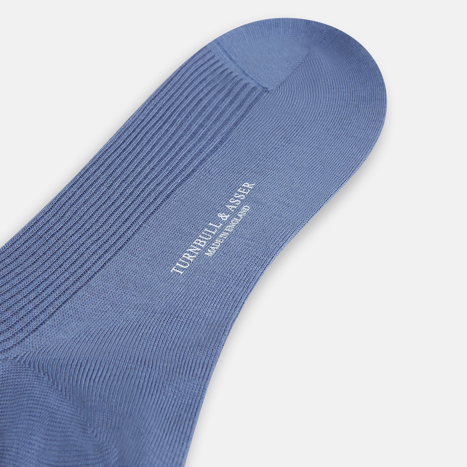 Image 3 of product A single Powder Blue Mid-Length Merino Sock by Turnbull & Asser stands upright against a white background, showcasing its smooth texture and subtle vertical lines, with a length that reaches just below the knee.