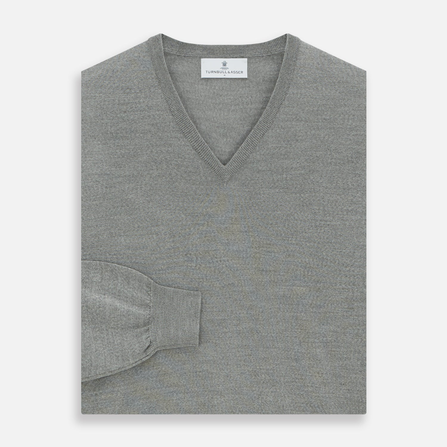 Image 3 of product The Grey V-Neck Merino Wool Jumper by Turnbull & Asser features long sleeves with ribbed cuffs and hem, making it a versatile wardrobe essential for any gentleman. Shown here in classic light grey on a white background.