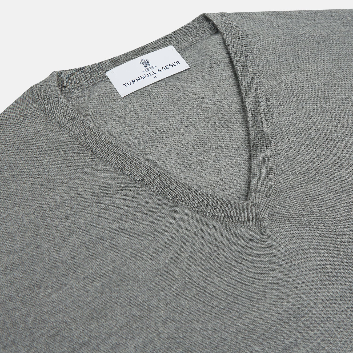 Image 2 of product The Grey V-Neck Merino Wool Jumper by Turnbull & Asser features long sleeves with ribbed cuffs and hem, making it a versatile wardrobe essential for any gentleman. Shown here in classic light grey on a white background.