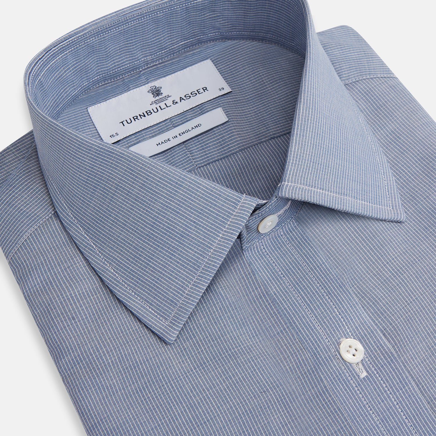 Image 2 of product The Turnbull & Asser Blue Pencil Stripe Mayfair Shirt is crafted from organic cotton with a classic collar, white buttons, and buttoned cuffs. Shown laid flat on a white background.