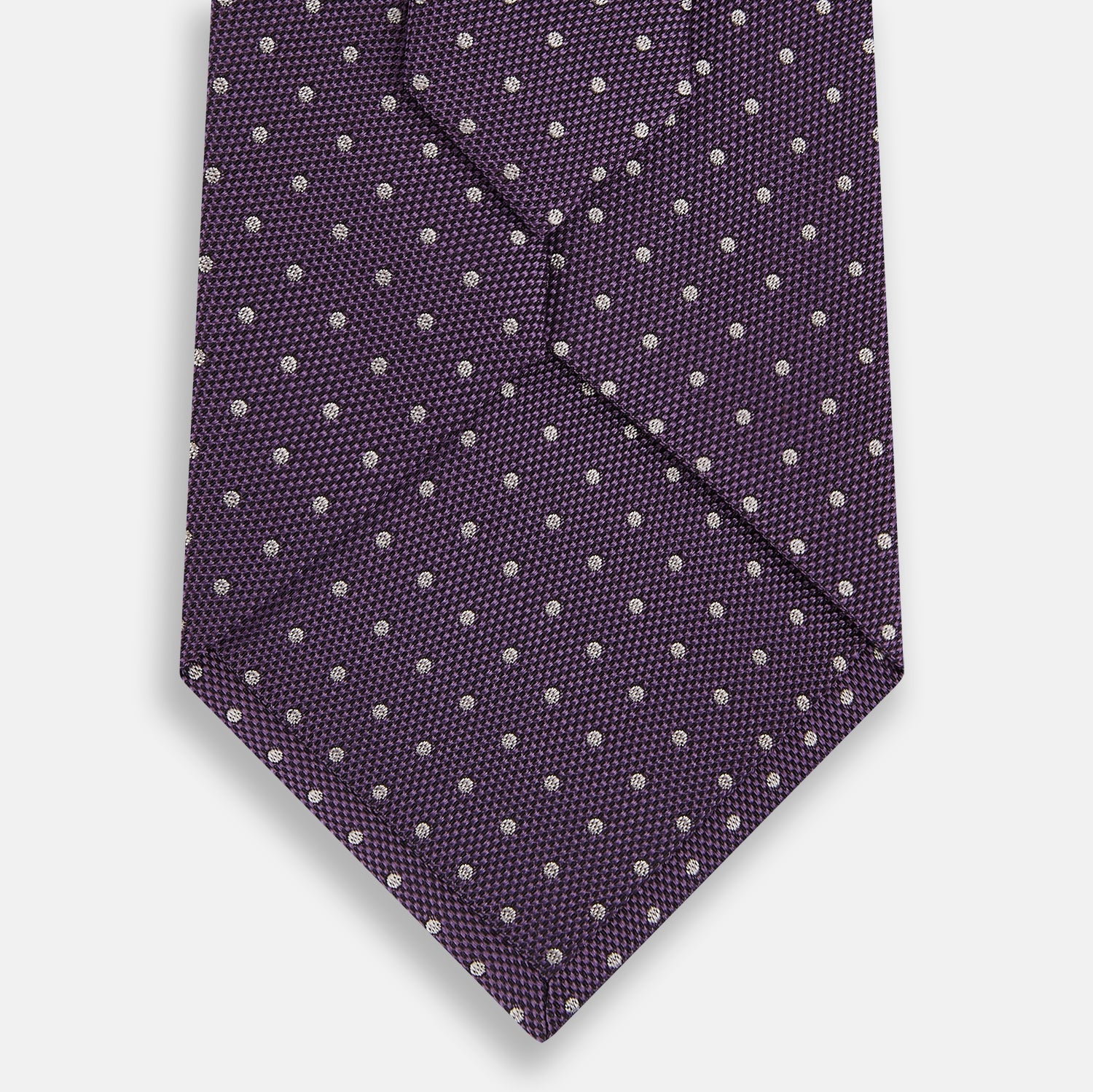 Image 3 of product The Turnbull & Asser Lilac and Purple Micro Dot Silk Tie, featuring a subtle white micro-dot pattern, is rolled up and displayed on a white background—an essential addition to any polished wardrobe.