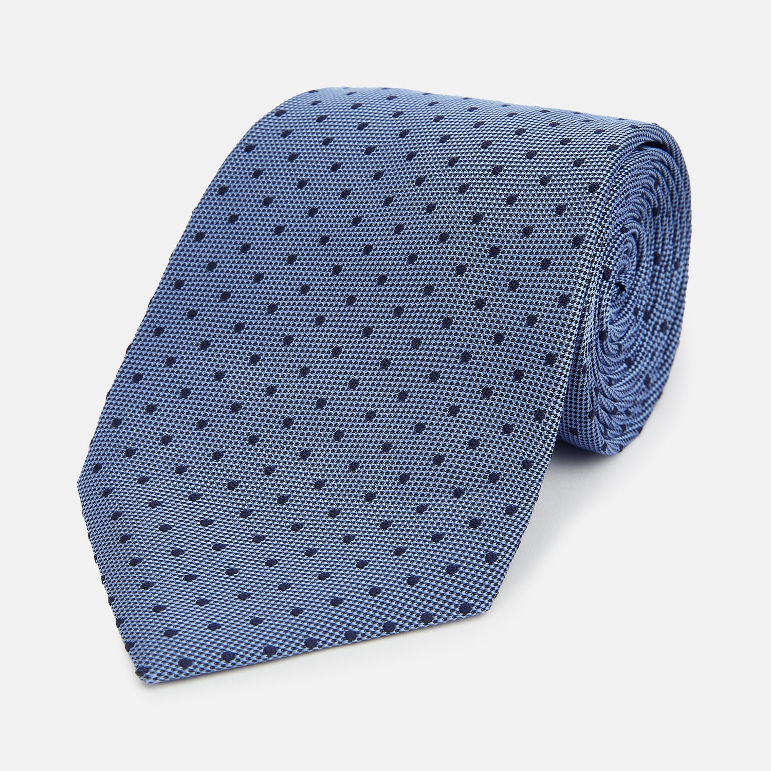Image 1 of product The Turnbull & Asser Navy and Blue Micro Dot Silk Tie is shown rolled up, featuring a steel blue color with small navy blue dots, on a plain white background.