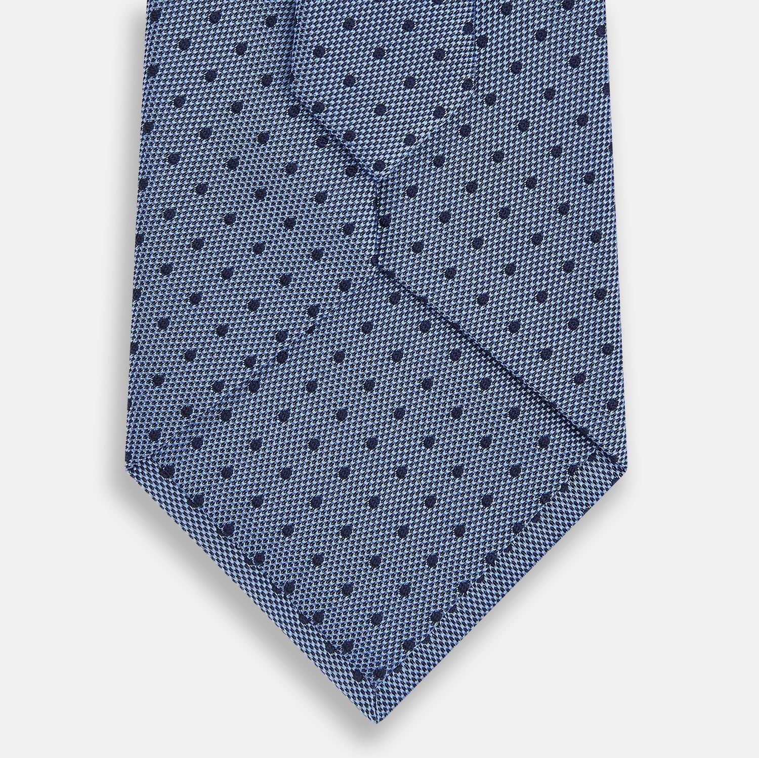 Image 3 of product The Turnbull & Asser Navy and Blue Micro Dot Silk Tie is shown rolled up, featuring a steel blue color with small navy blue dots, on a plain white background.