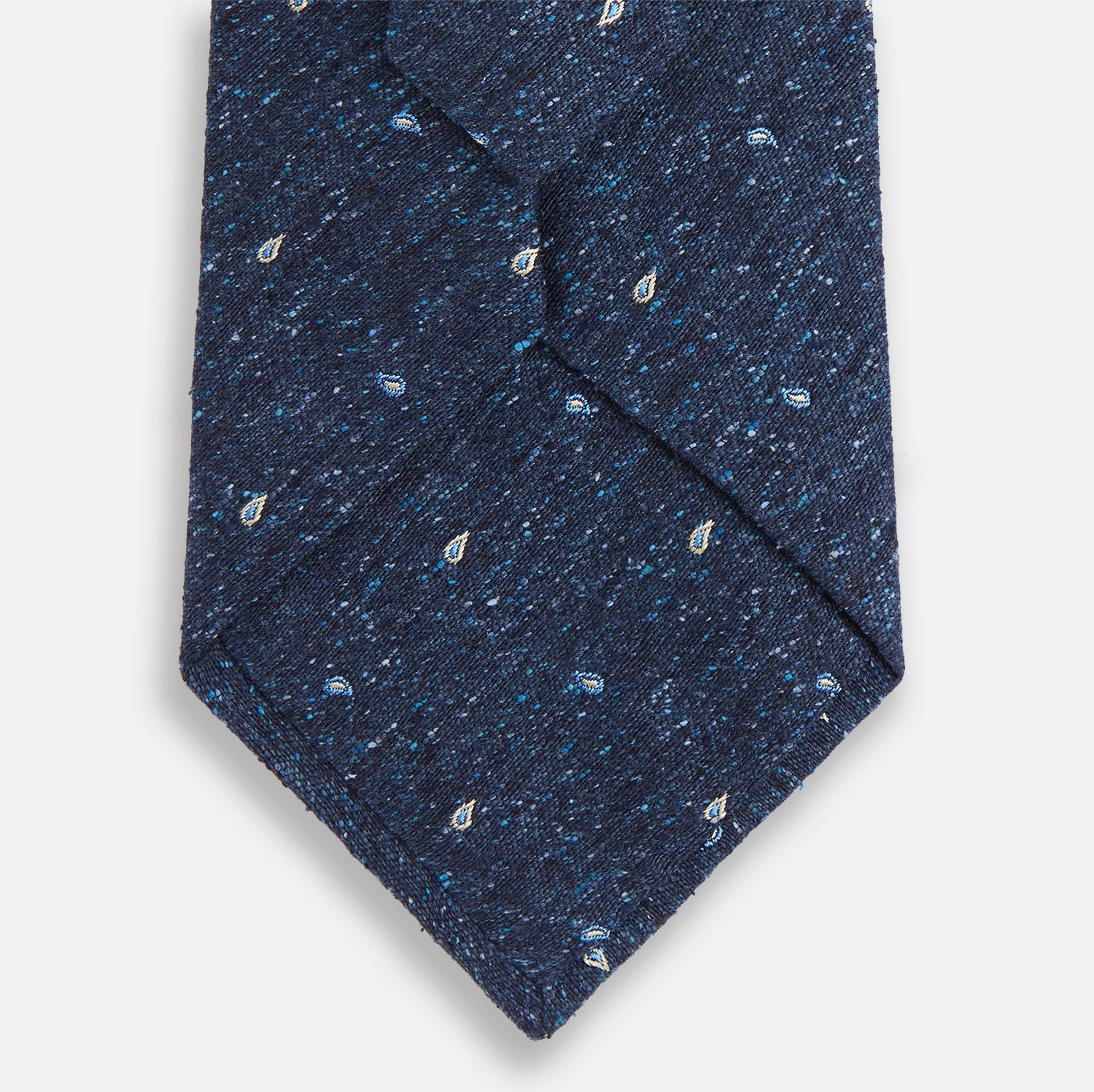 Image 3 of product The Turnbull & Asser Navy Micro Paisley Silk Tie features a rolled-up navy blue silk with a subtle speckled texture and small light blue paisley patterns, perfect for enhancing any formal collection, shown on a white background.
