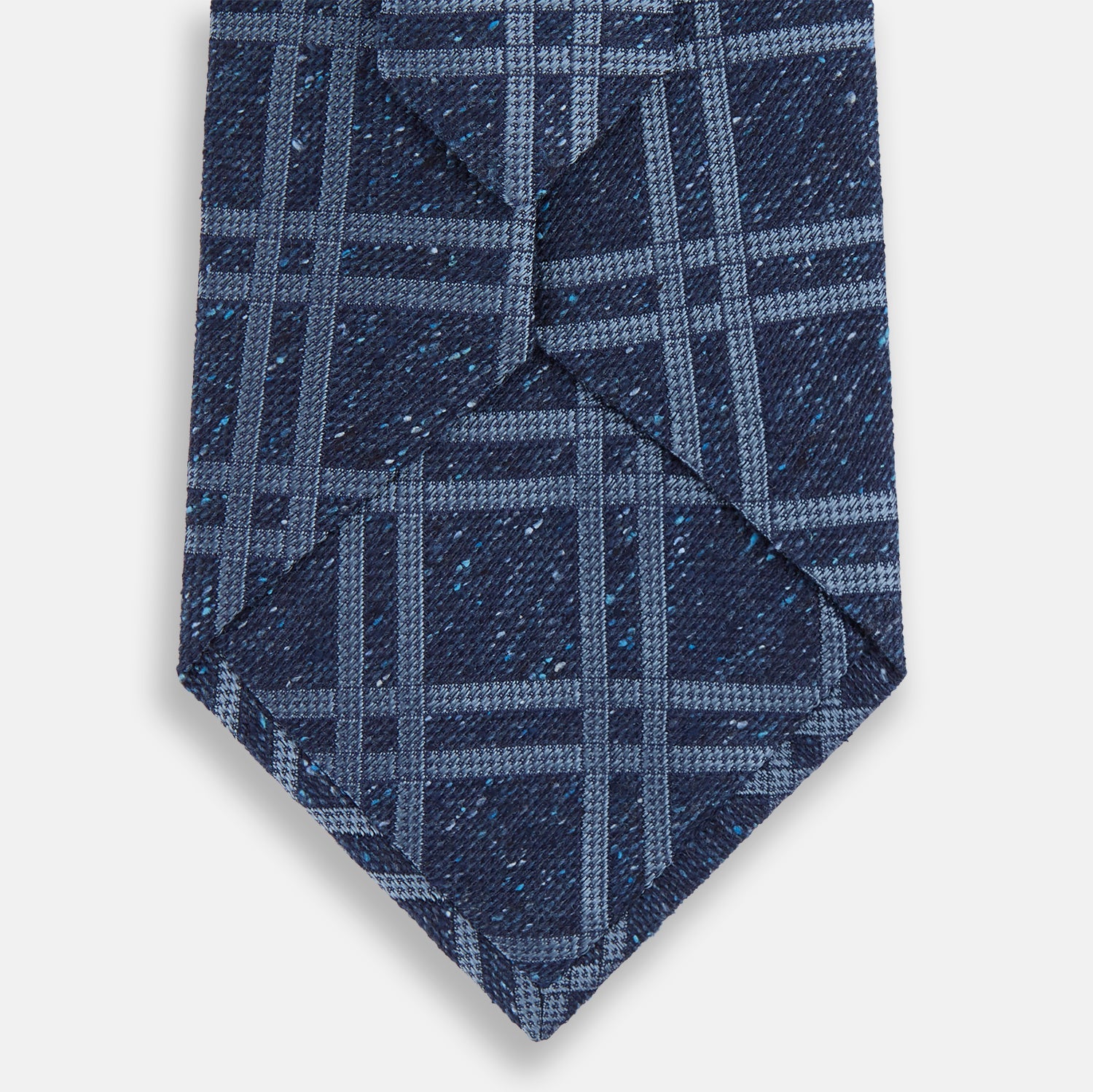 Image 3 of product The Turnbull & Asser Navy Bold Double Check Silk Tie features a textured navy fabric with a light blue windowpane plaid pattern. This handmade silk tie is neatly rolled on a white background.