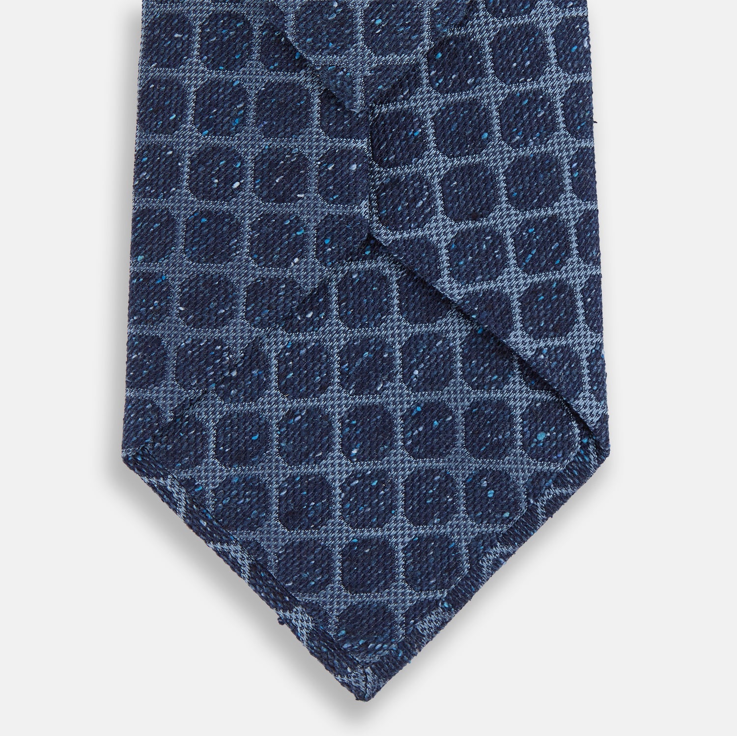Image 3 of product The Turnbull & Asser Navy Grid Silk Tie is handmade and neatly rolled, showcasing a dark blue silk fabric with a textured grid pattern, displayed on a plain white background.
