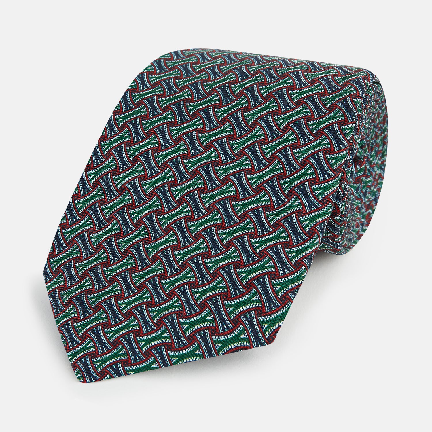 Image 1 of product The Forest Green and Red Weave Patterned Silk Tie by Turnbull & Asser features a geometric interlocking design in red, blue, and green, elegantly rolled on a white background.