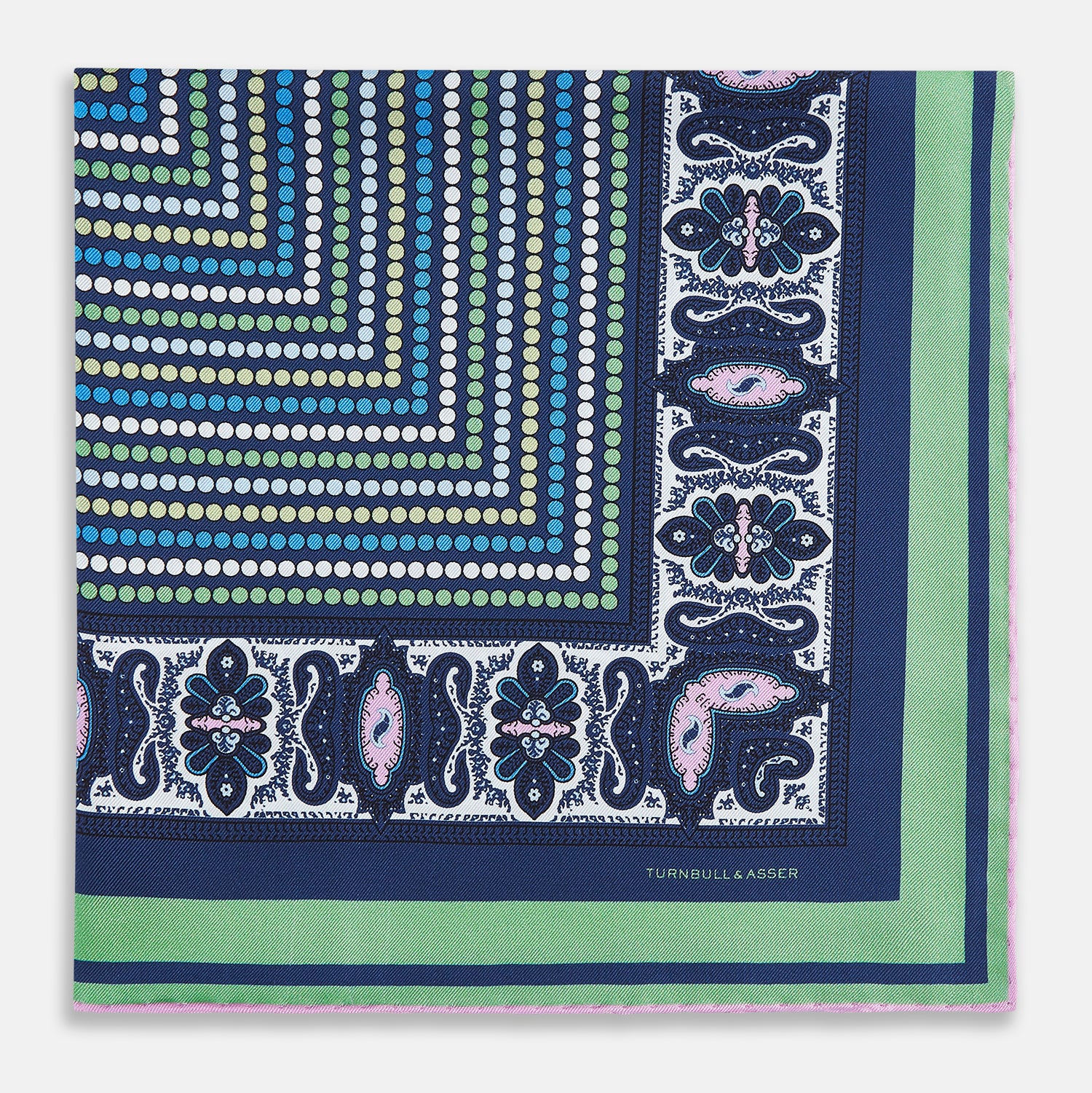 Image 3 of product The Turnbull & Asser Oxford Blue Dots and Paisley Silk Pocket Square is handcrafted in England and features a blue, green, and white polka dot pattern with a paisley and floral border, plus the brand’s signature logo in the corner.