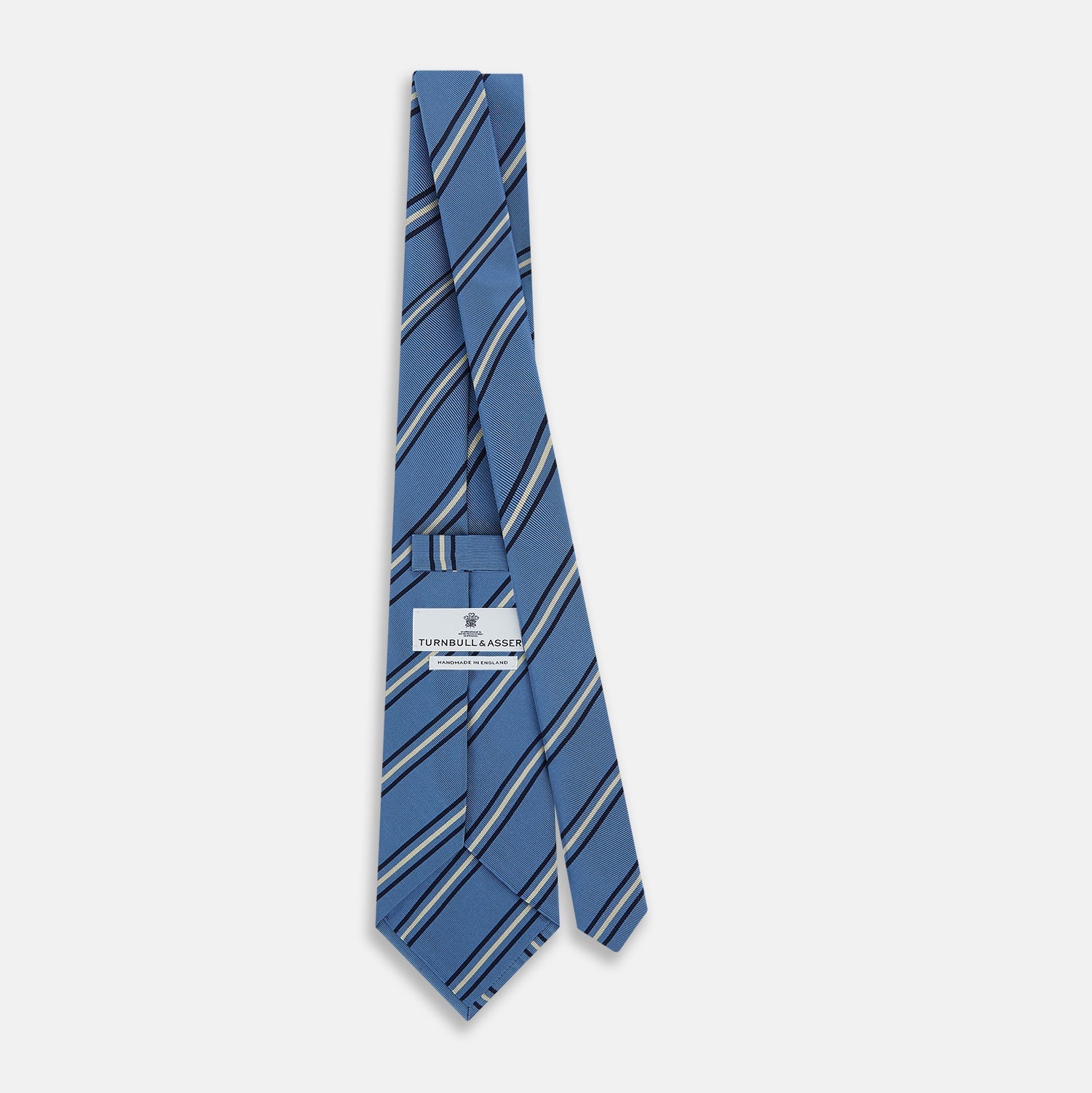 Image 4 of product The Blue Multi Stripe Silk Blend Tie by Turnbull & Asser features diagonal navy and light beige stripes, shown rolled up on a white background—a timeless formal accessory.