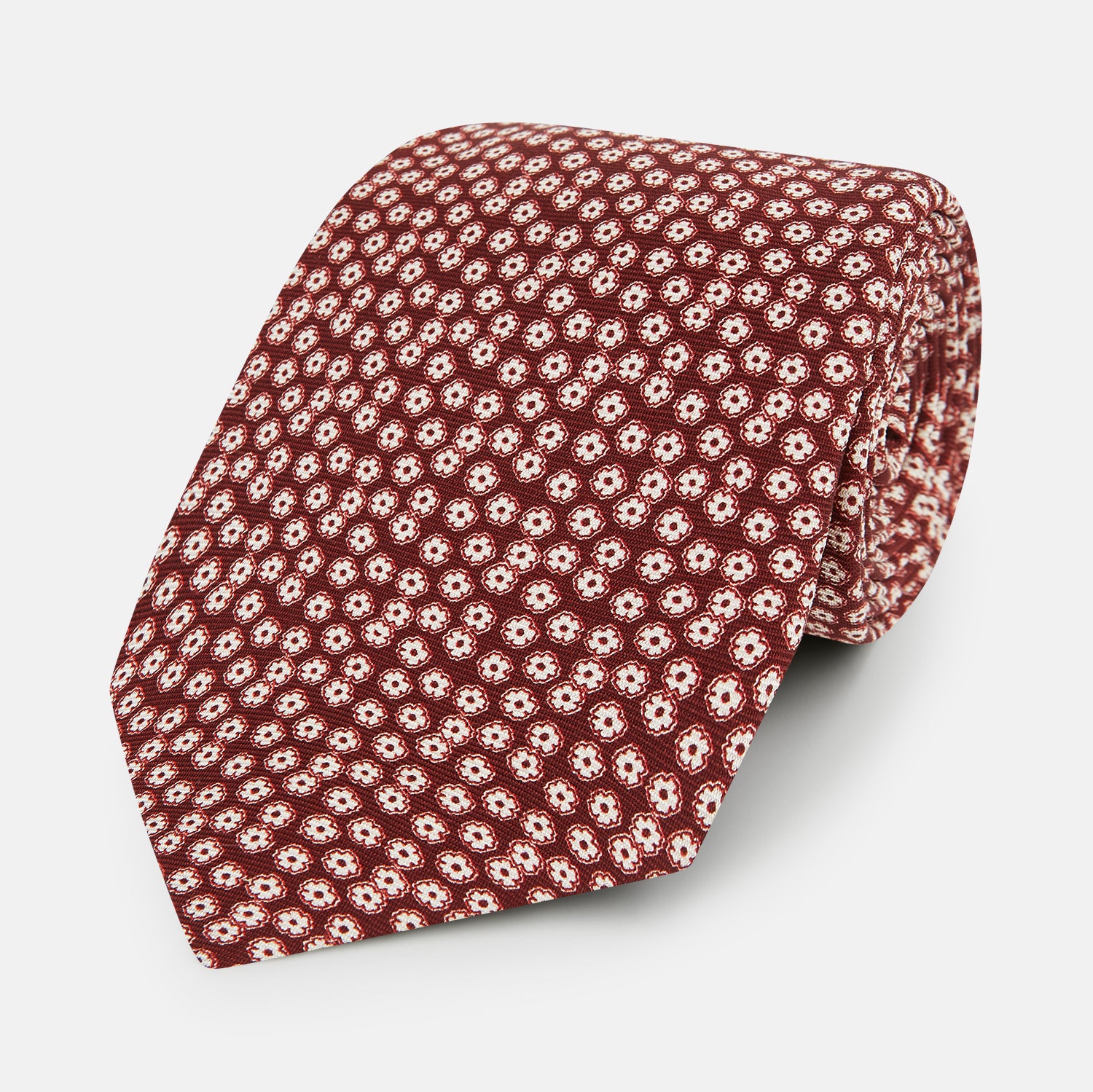 Image 1 of product Turnbull & Asser's Burgundy Flower Patterned Silk Tie features small white and light red floral circles, shown rolled on a plain white background.
