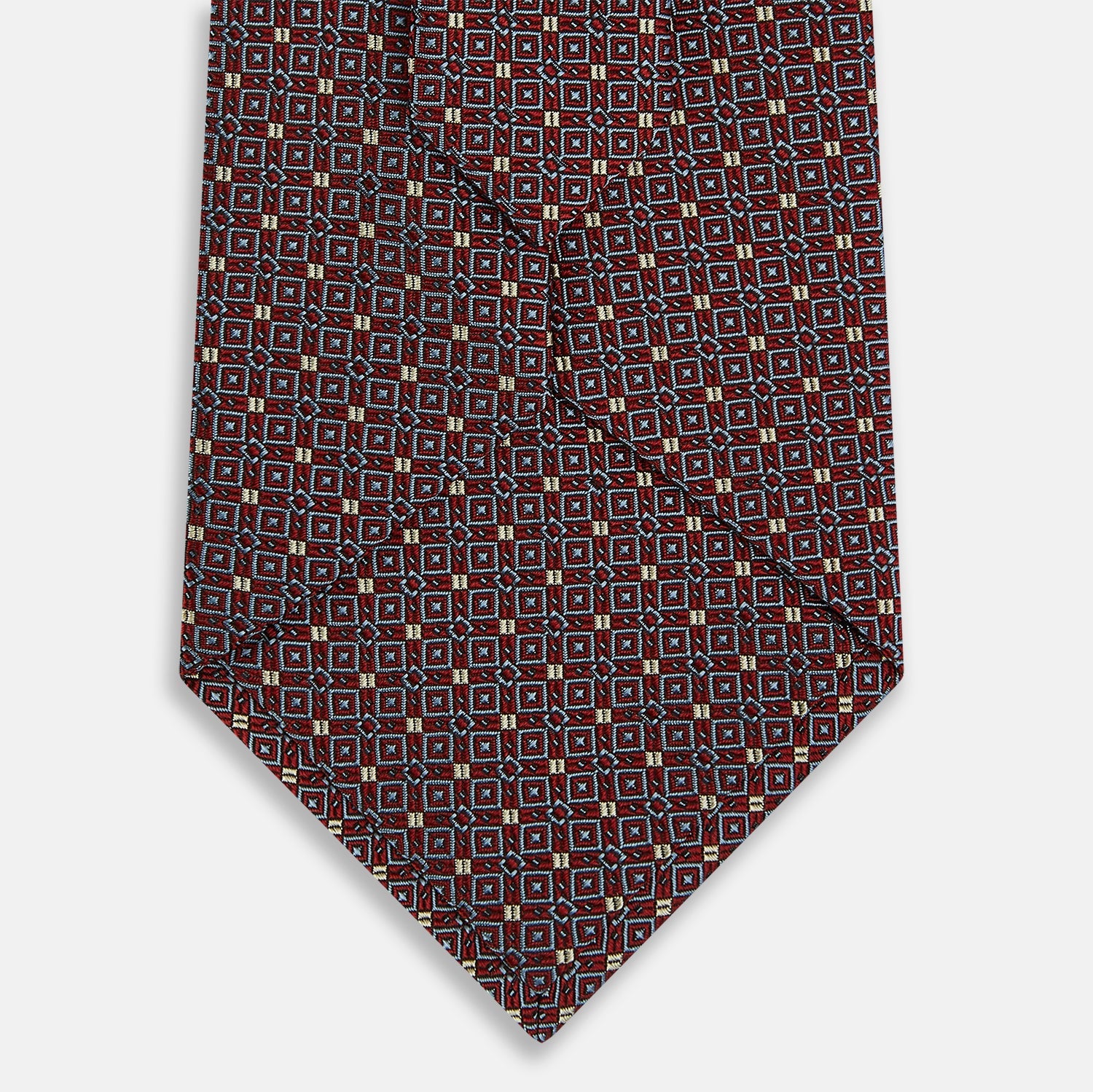 Image 3 of product The Turnbull & Asser Burgundy Geometric Silk Tie, crafted in Britain, features a repeating pattern of light blue and white squares and diamonds. The neatly rolled tie is shown against a plain white background.