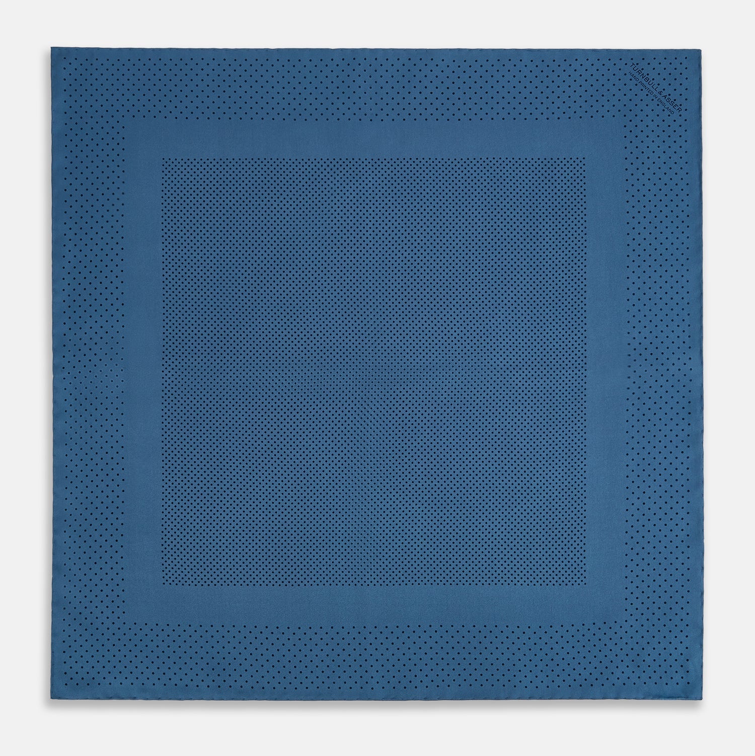 Image 4 of product The Blue Dot Silk Pocket Square by Turnbull & Asser features small black polka dots on blue silk and is made in England. The image shows it neatly folded, with a corner turned down to display both sides.