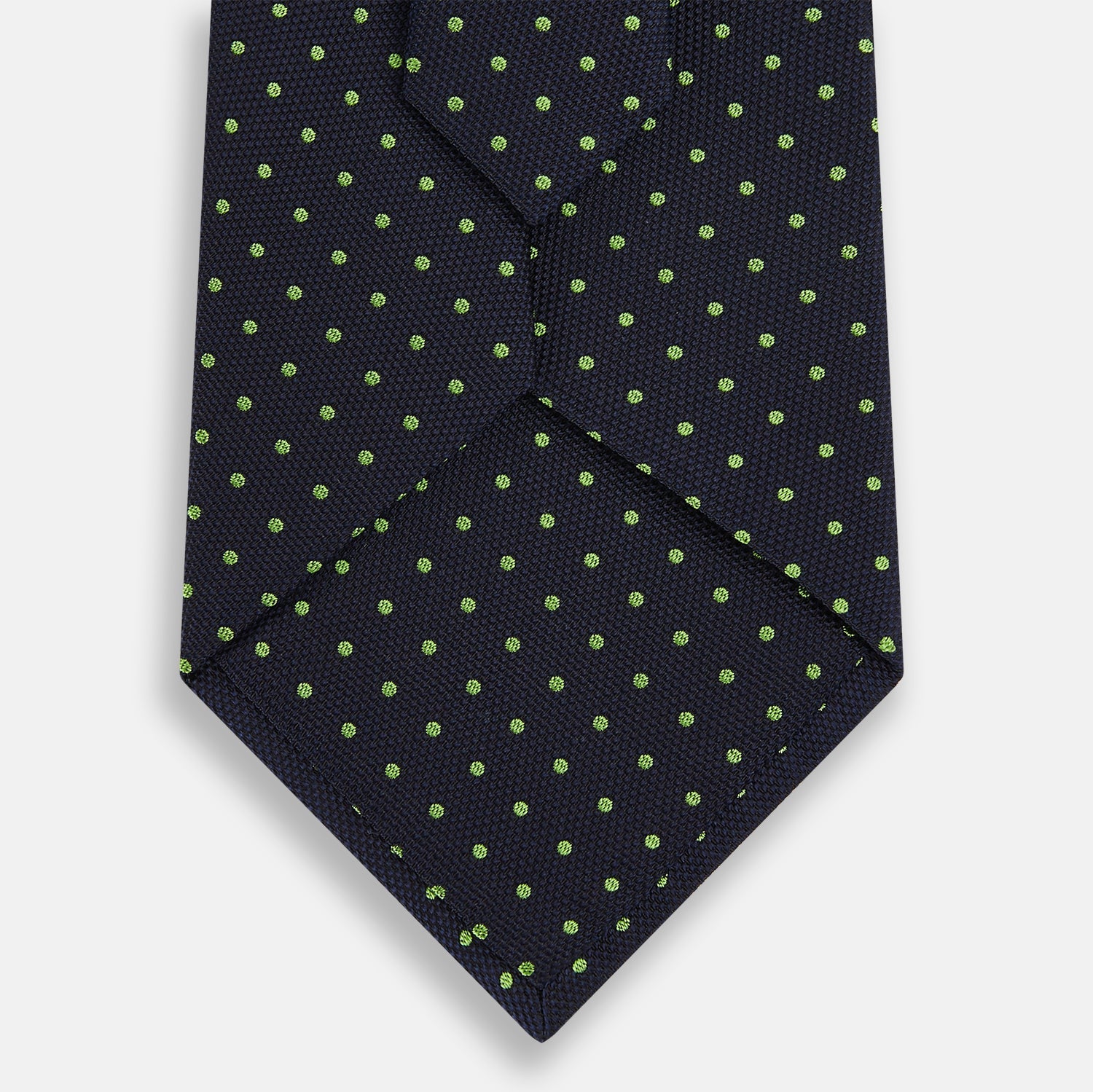 Image 3 of product The Turnbull & Asser Green and Navy Micro Dot Silk Tie features small green dots on a navy silk background, displayed rolled up on white.