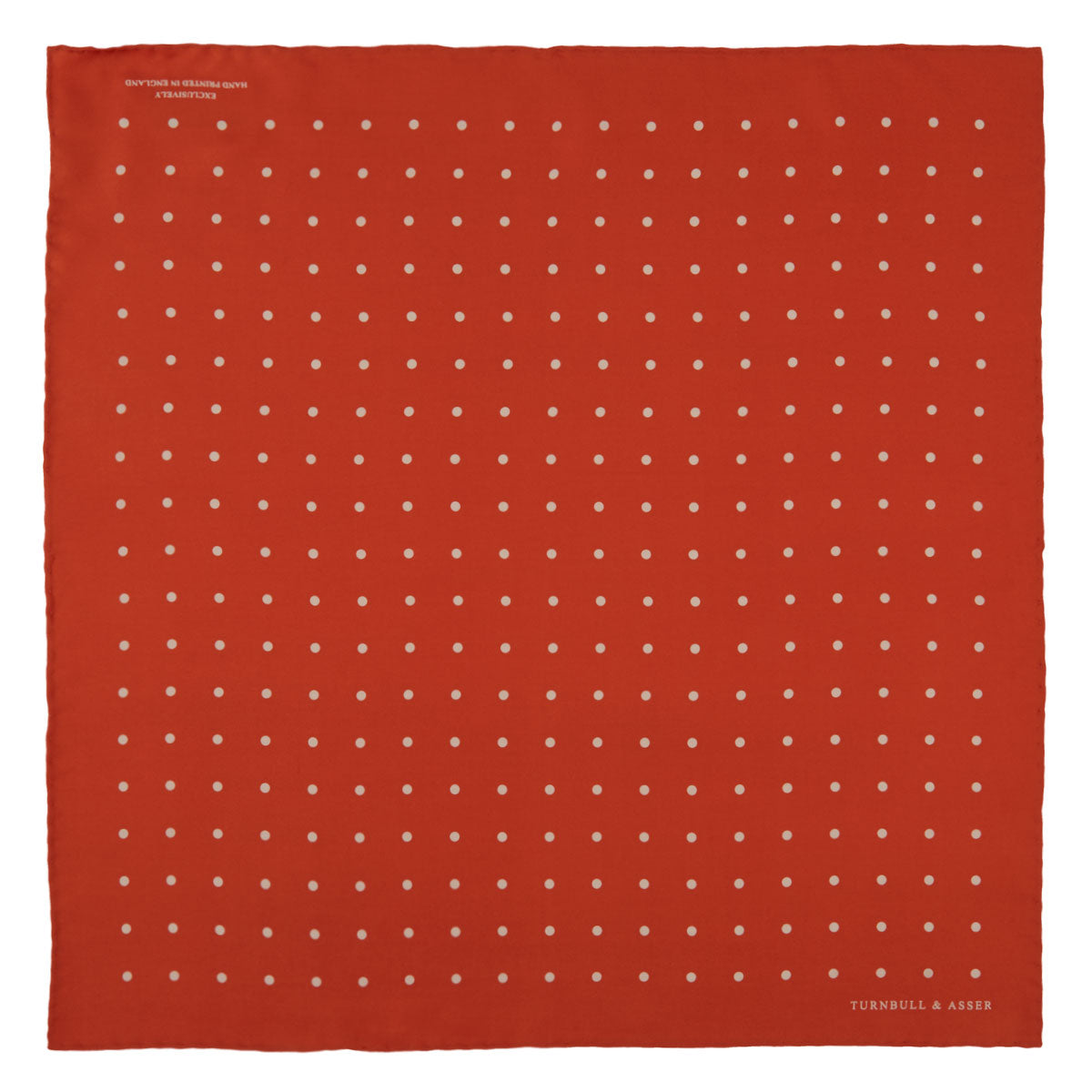 Image 2 of product The Orange Spot Silk Pocket Square by Turnbull & Asser features evenly spaced white polka dots and the brand’s name in one corner, making this dapper accessory a standout addition to any outfit.