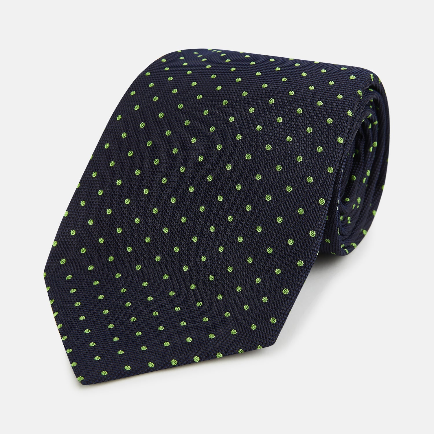 Image 1 of product The Turnbull & Asser Green and Navy Micro Dot Silk Tie features small green dots on a navy silk background, displayed rolled up on white.