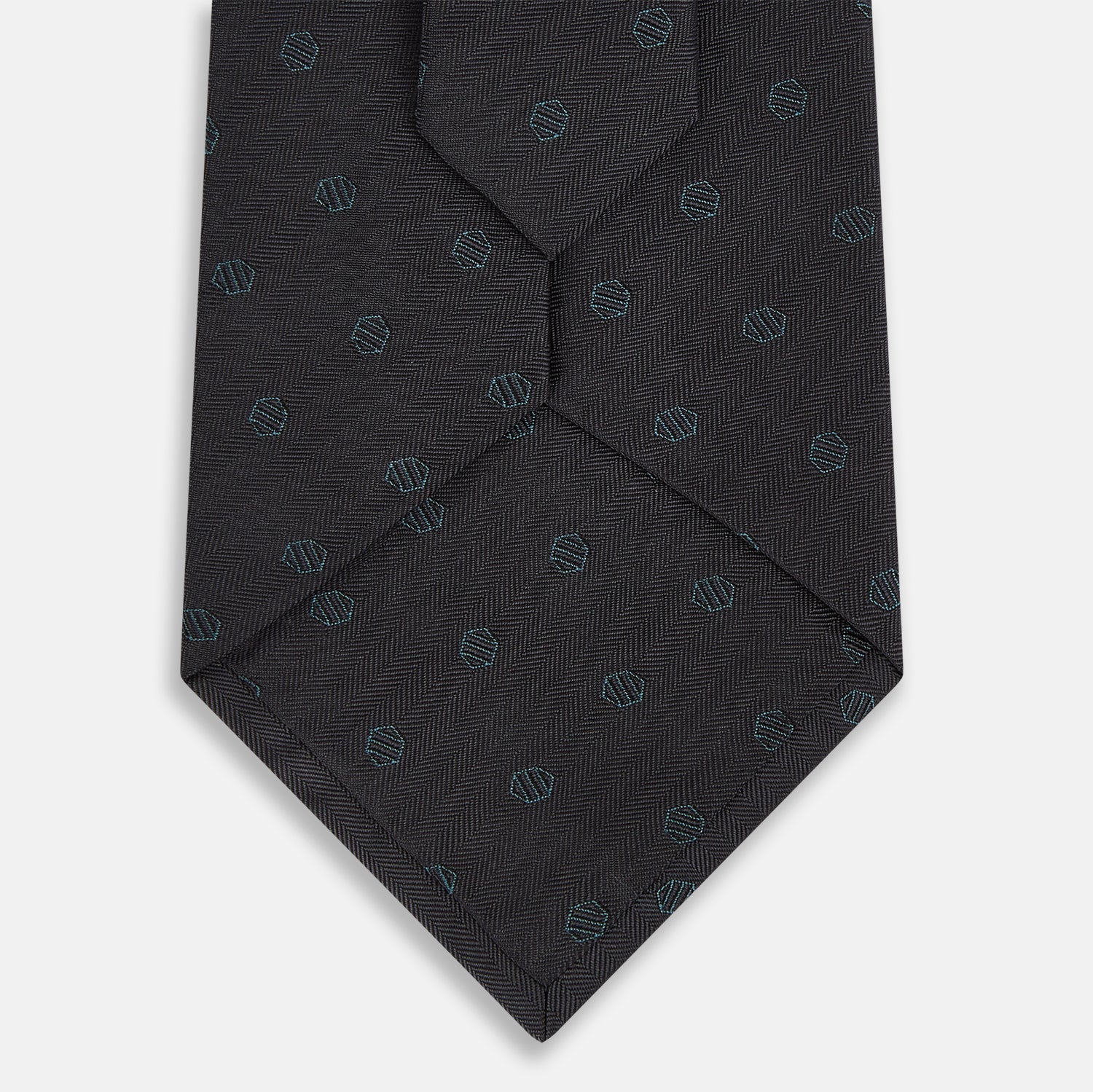 Image 3 of product The Turnbull & Asser Teal and Navy Circle Silk Tie features a subtle herringbone pattern with small repeating circle motifs, displayed neatly rolled on a white background.