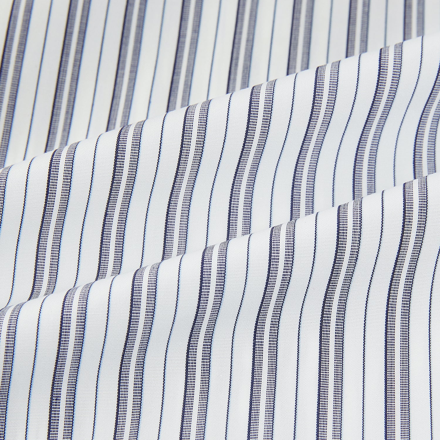 Image 6 of product The Turnbull & Asser Navy Multi Stripe Mayfair Shirt, a pure cotton button-up with long sleeves and a collar, features thin vertical blue and white stripes and is displayed flat on a white background.